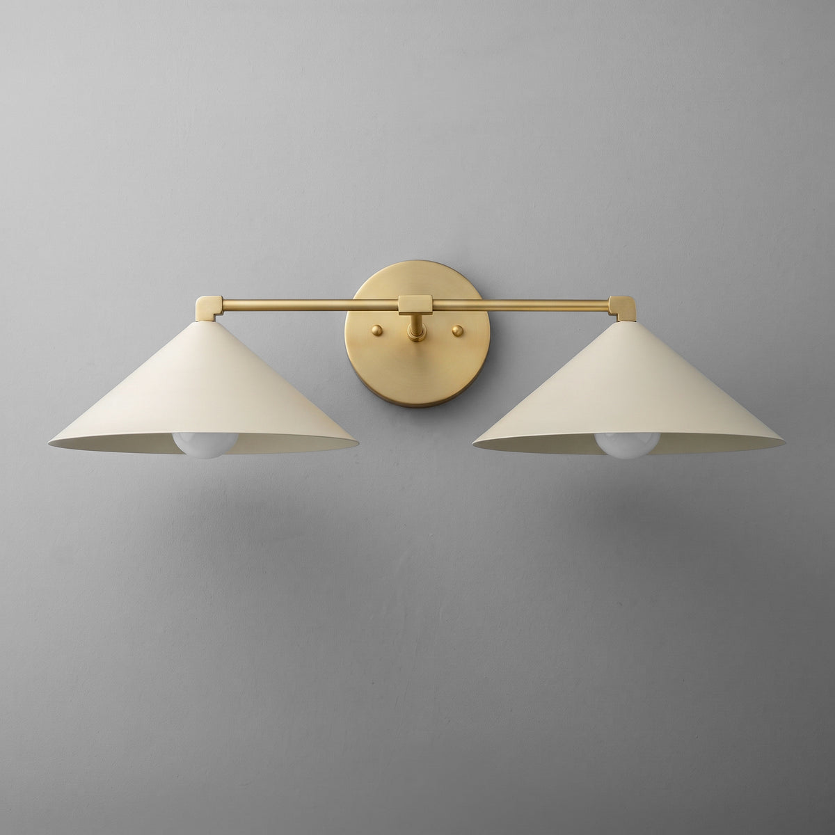 Two-light vanity light in Raw or Sealed Brass with wide steel cone shades on a straight arm and a round wall plate. - VANITY LIGHT MODEL NO. 1185