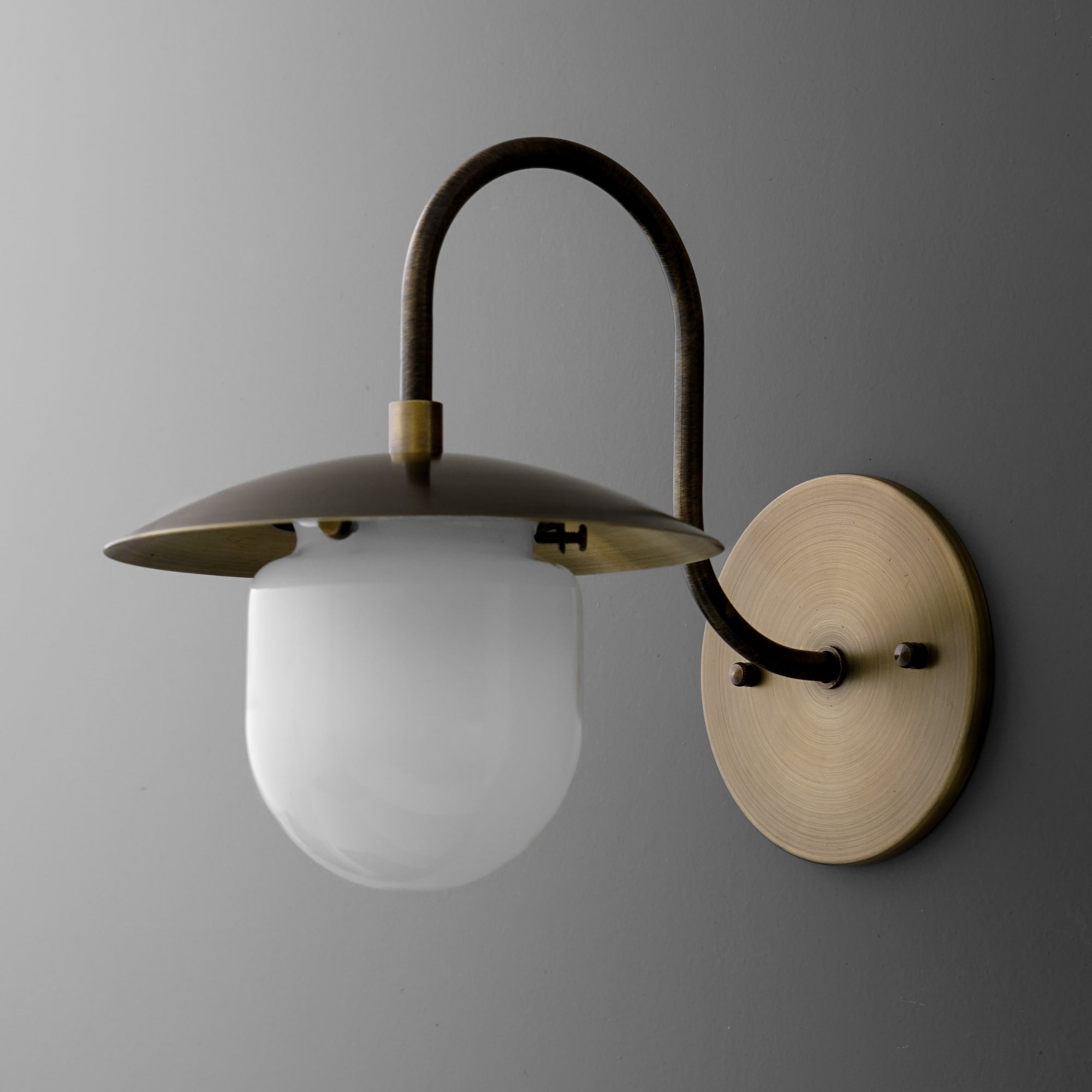 Antique brass wall sconce with curved arm and frosted glass globe shade. - SCONCE MODEL NO. 7191