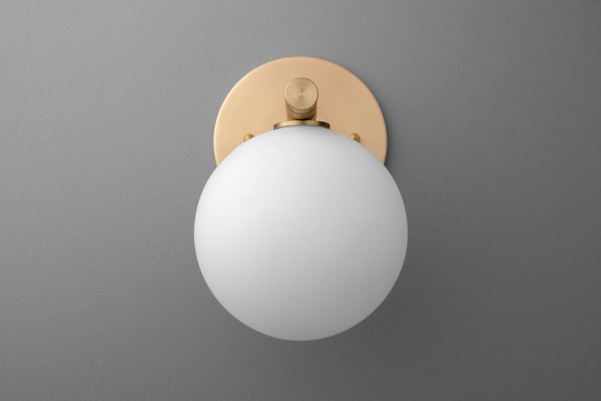 Round white glass globe wall sconce with raw brass circular base on gray background. - SCONCE MODEL NO. 0904