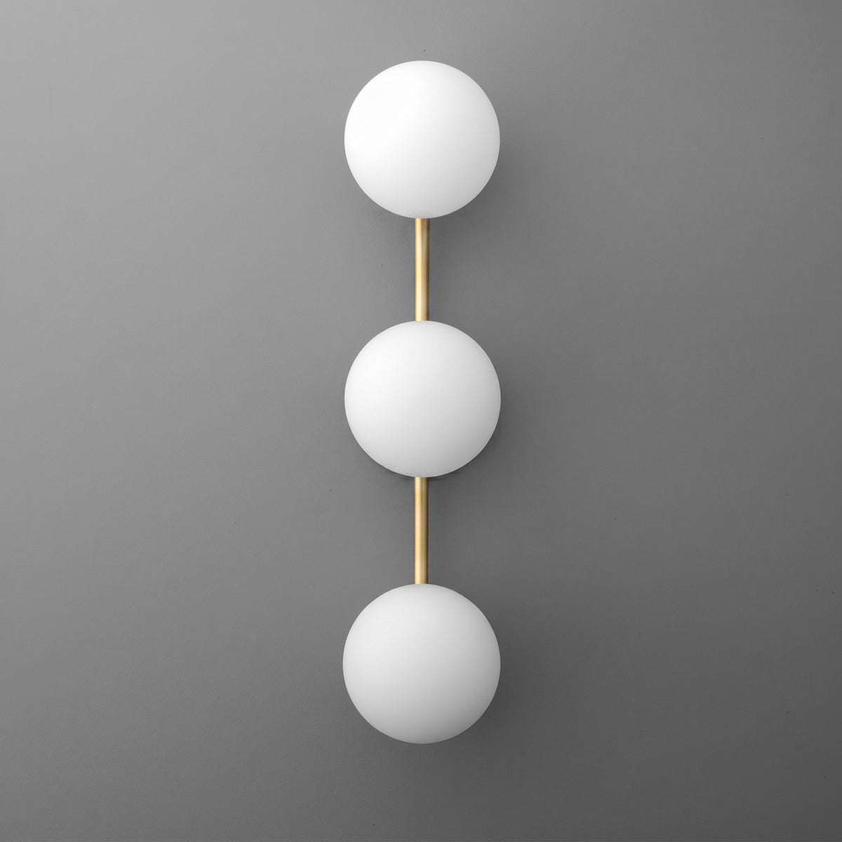 Modern wall sconce with three white glass globes aligned vertically on a gold metal frame. - SCONCE MODEL NO. 9250