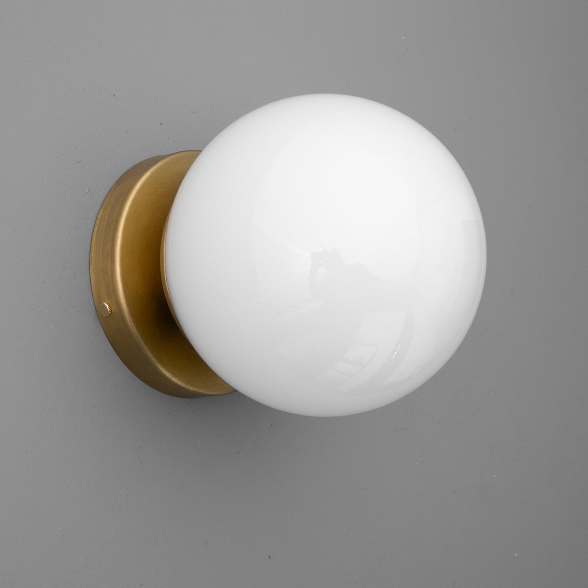 Round white glass globe sconce with brass circular wall mount, modern minimalist design. - SCONCE MODEL NO. 3825