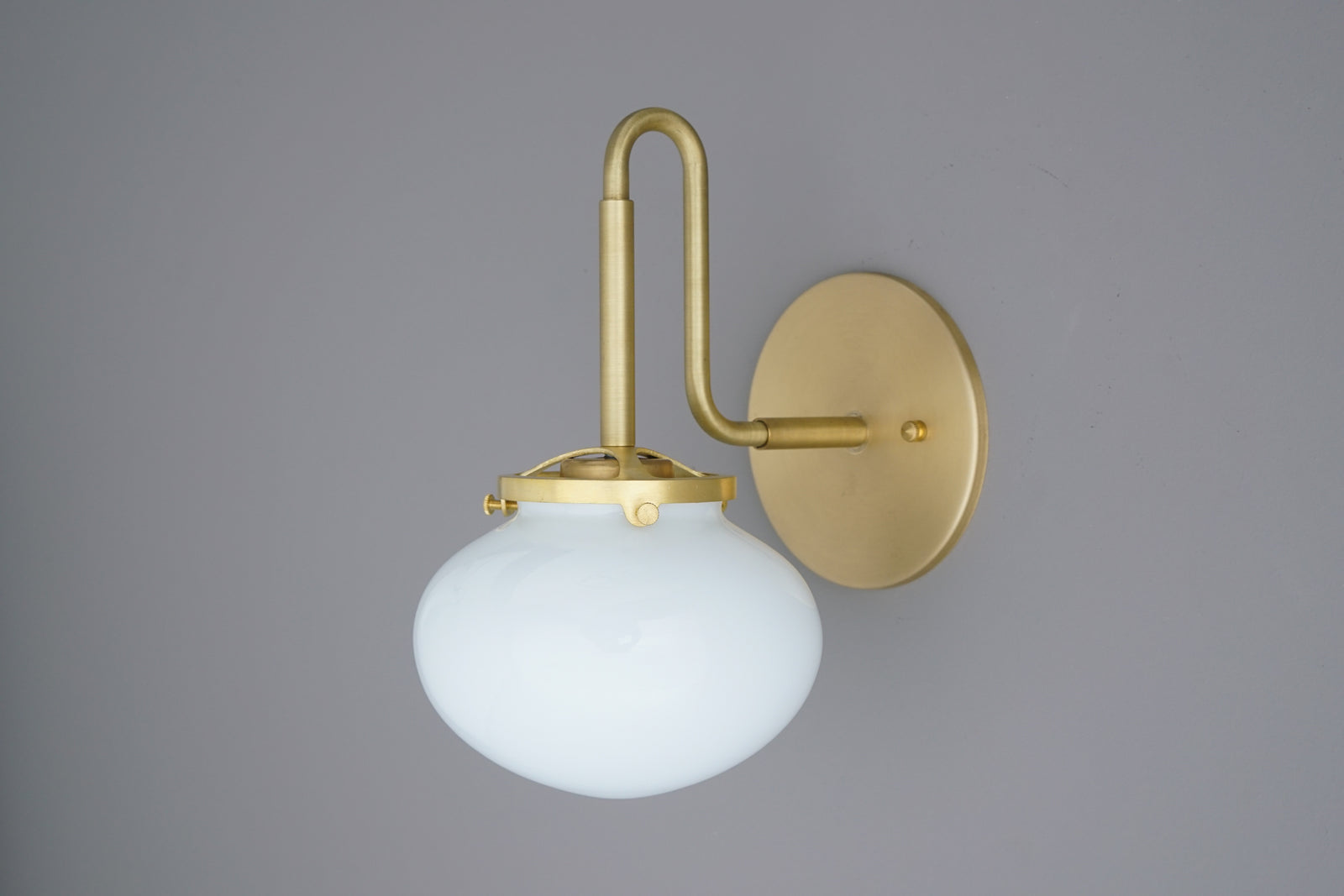 Matte gold metal wall sconce with a curved arm and frosted white glass globe shade. - SCONCE MODEL NO. 9452