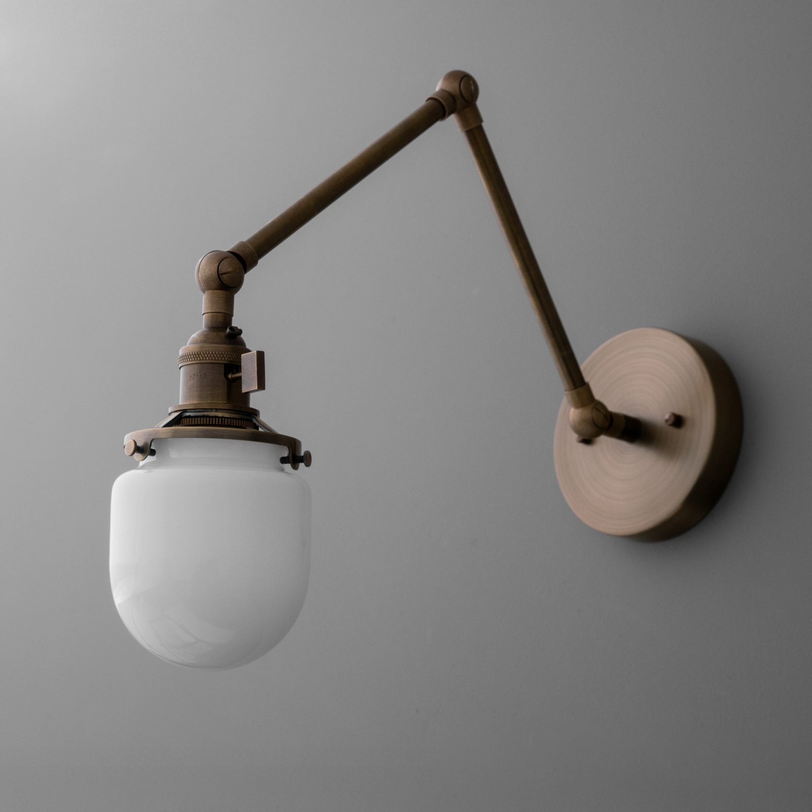 Wall-mounted sconce with adjustable bronze arm and frosted white glass globe shade. - SCONCE MODEL NO. 7575