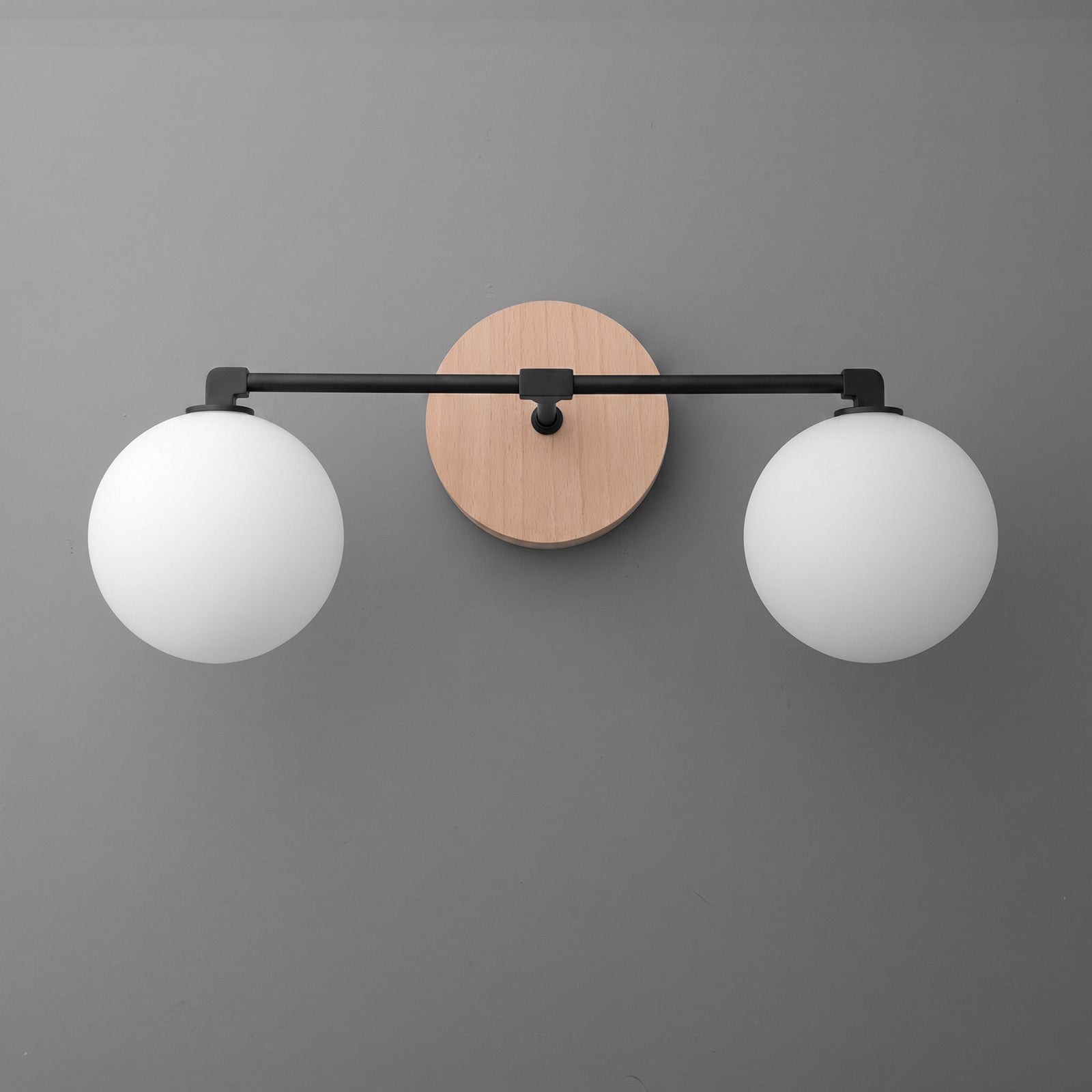 Modern two-bulb vanity light with round white glass shades and black metal arms on a circular wood backplate. - VANITY LIGHT MODEL NO. 1151