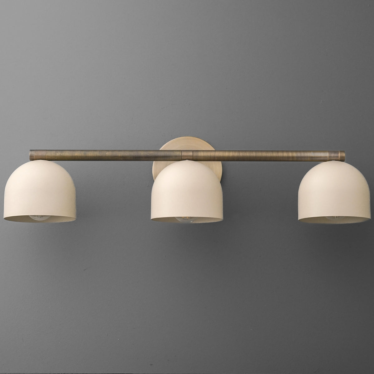 Three-bulb vanity light with brushed metal bar and matte white dome shades mounted on round base. - VANITY LIGHT MODEL NO. 1169