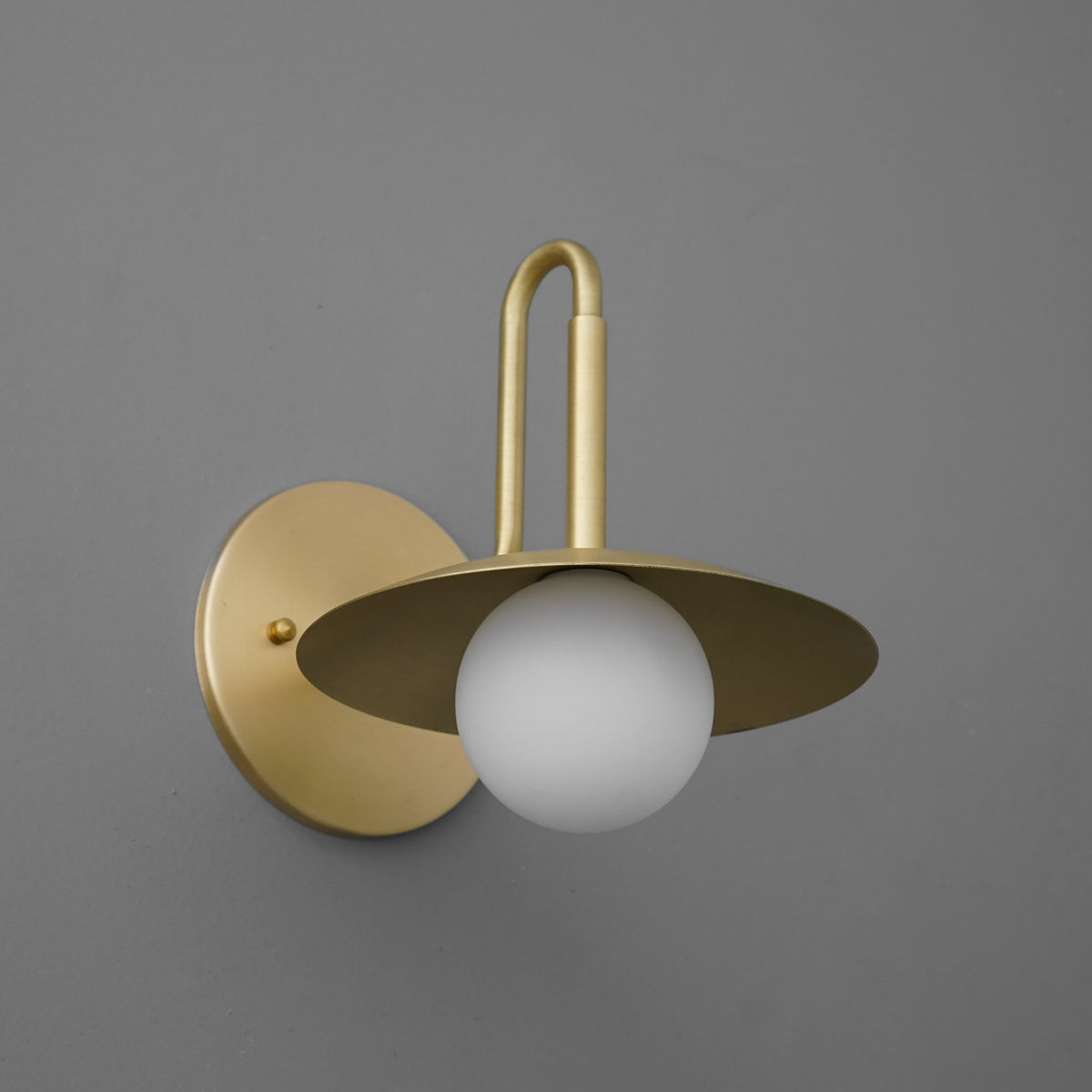 Matte gold metal wall sconce with flat circular shade and frosted white globe bulb. - SCONCE MODEL NO. 1013