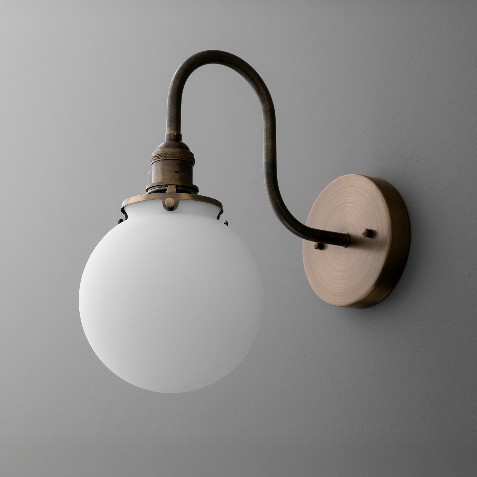 Wall-mounted sconce with curved dark metal arm and round white glass globe shade. - SCONCE MODEL NO. 0017