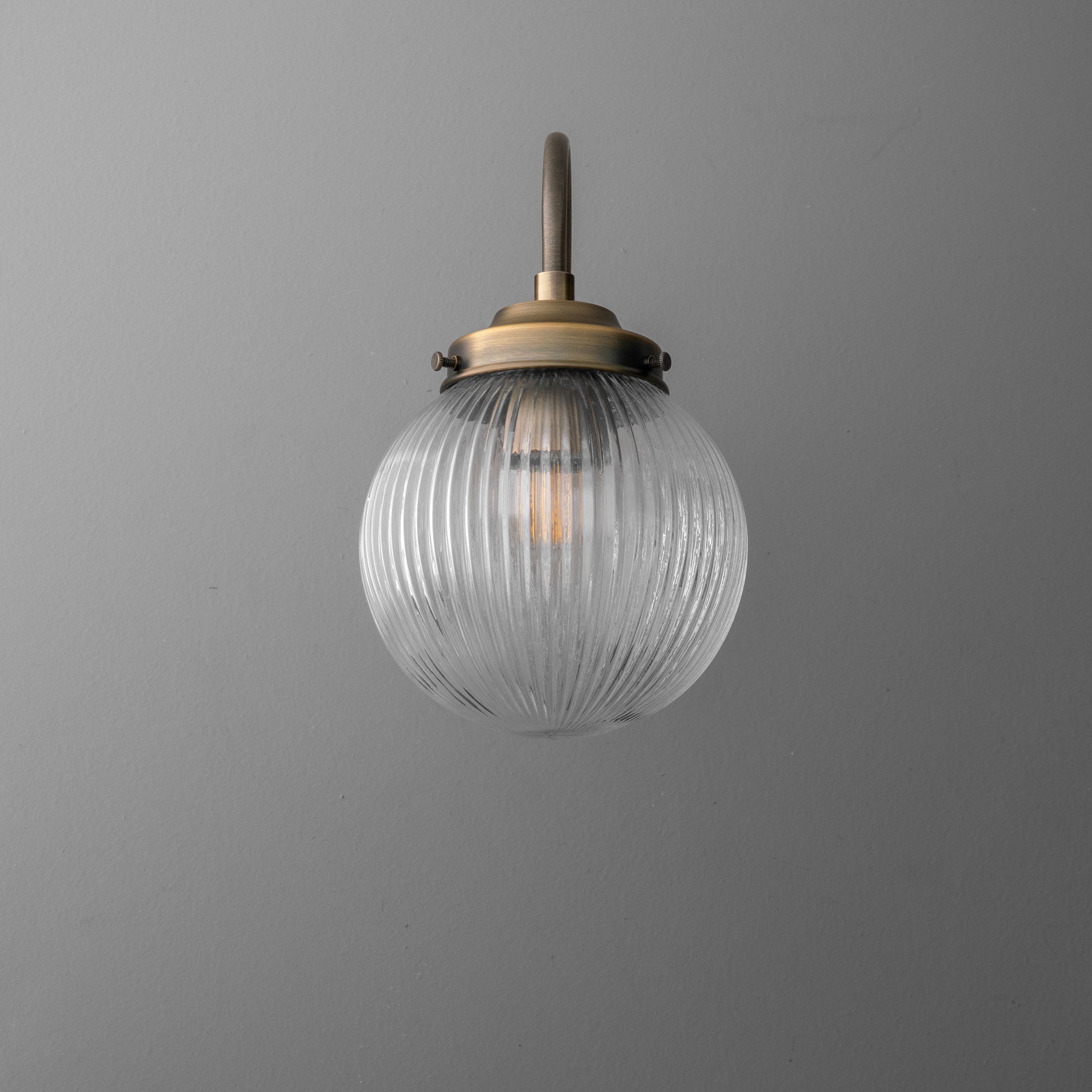 Wall-mounted sconce with ribbed clear glass globe and antique brass finish fixture. - SCONCE MODEL NO. 0691