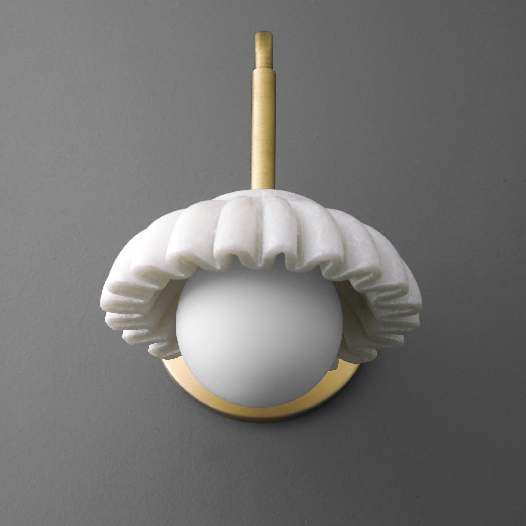 Wall sconce with a white ruffled ceramic shade and a brass mounting arm against a gray background. - SCONCE MODEL NO. 8633
