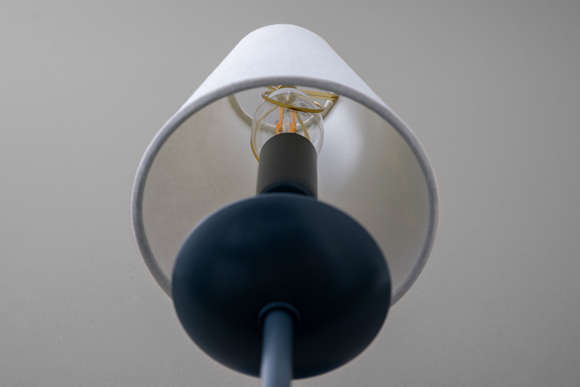 Wall sconce with coal blue matte base and white fabric lampshade against gray background. - SCONCE MODEL NO. 7085