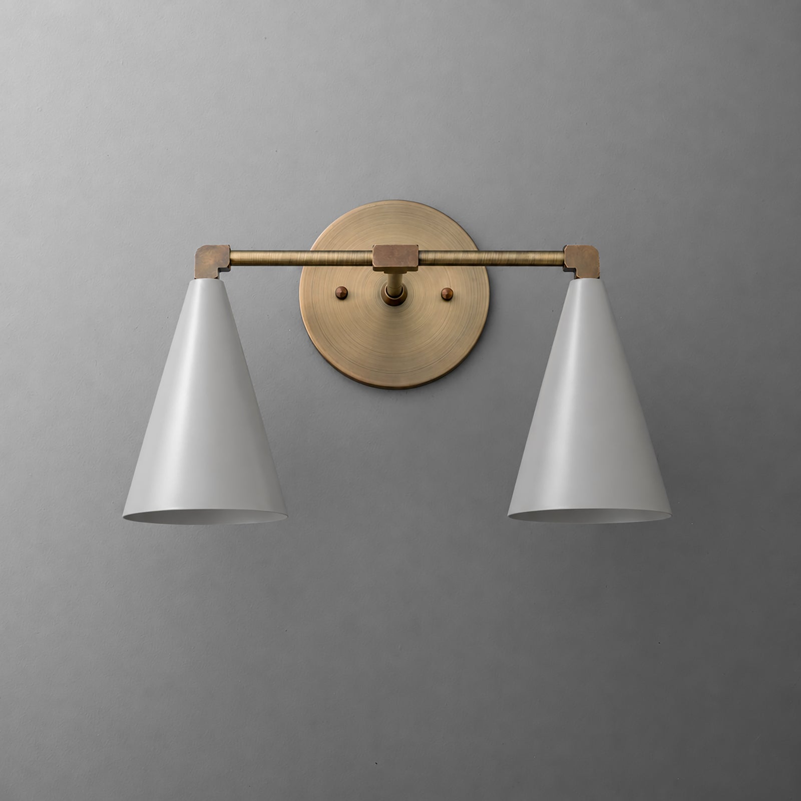 Two-light vanity light in Antique Brass with Gray cone shades on a straight arm and a round wall plate. - VANITY LIGHT MODEL NO. 1184