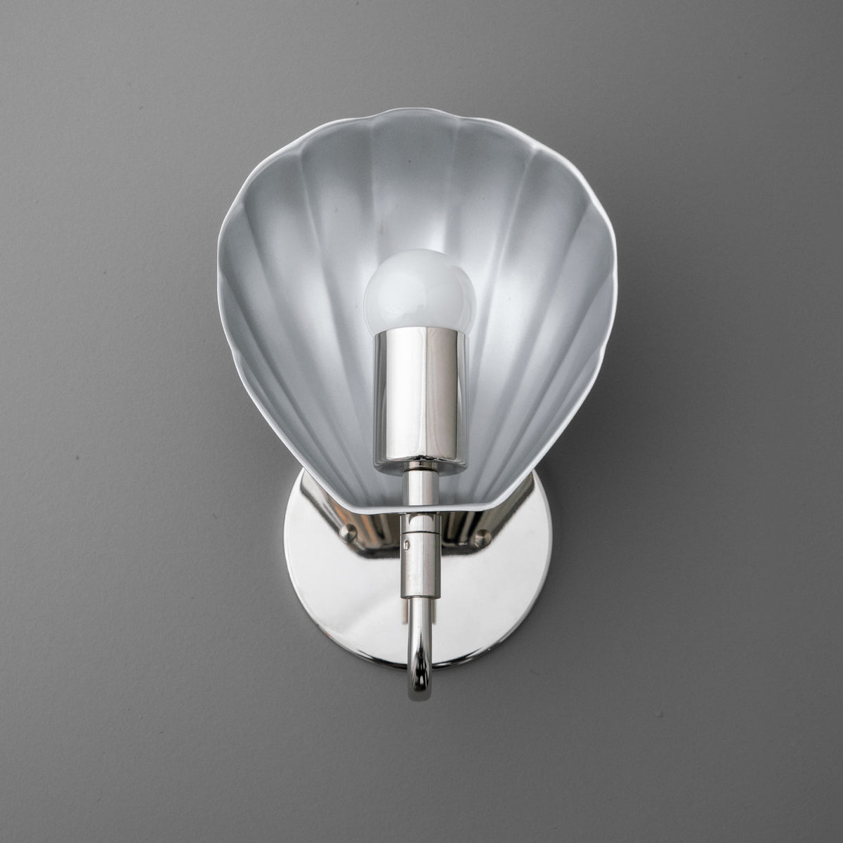 Silver metal wall sconce with scalloped shell-shaped backplate and single exposed bulb. - SCONCE MODEL NO. 1086