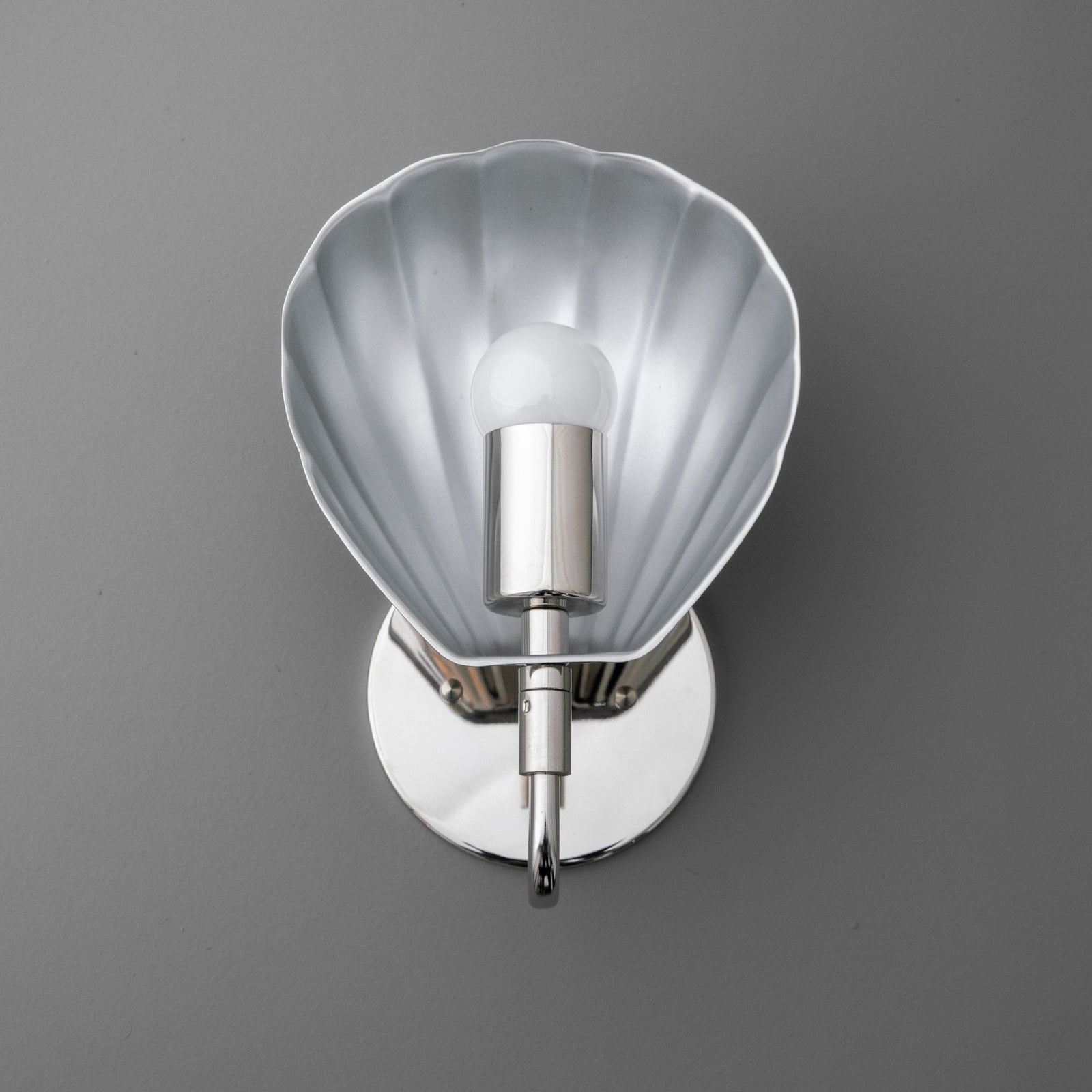 Silver metal wall sconce with scalloped shell-shaped backplate and single exposed bulb. - SCONCE MODEL NO. 1086