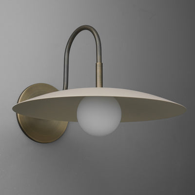 Antique brass wall sconce with curved arm and cream flat disc shade over frosted globe bulb. - SCONCE MODEL NO. 9171