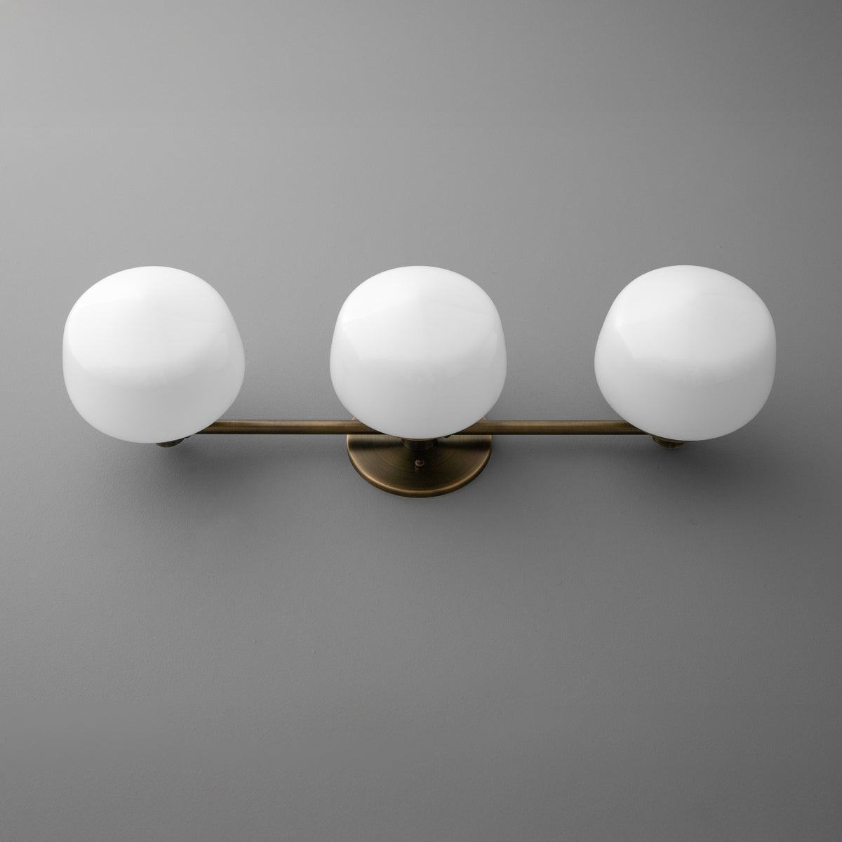 Wall-mounted vanity light with three round white glass globes on a horizontal bronze base. - VANITY LIGHT MODEL NO. 1106