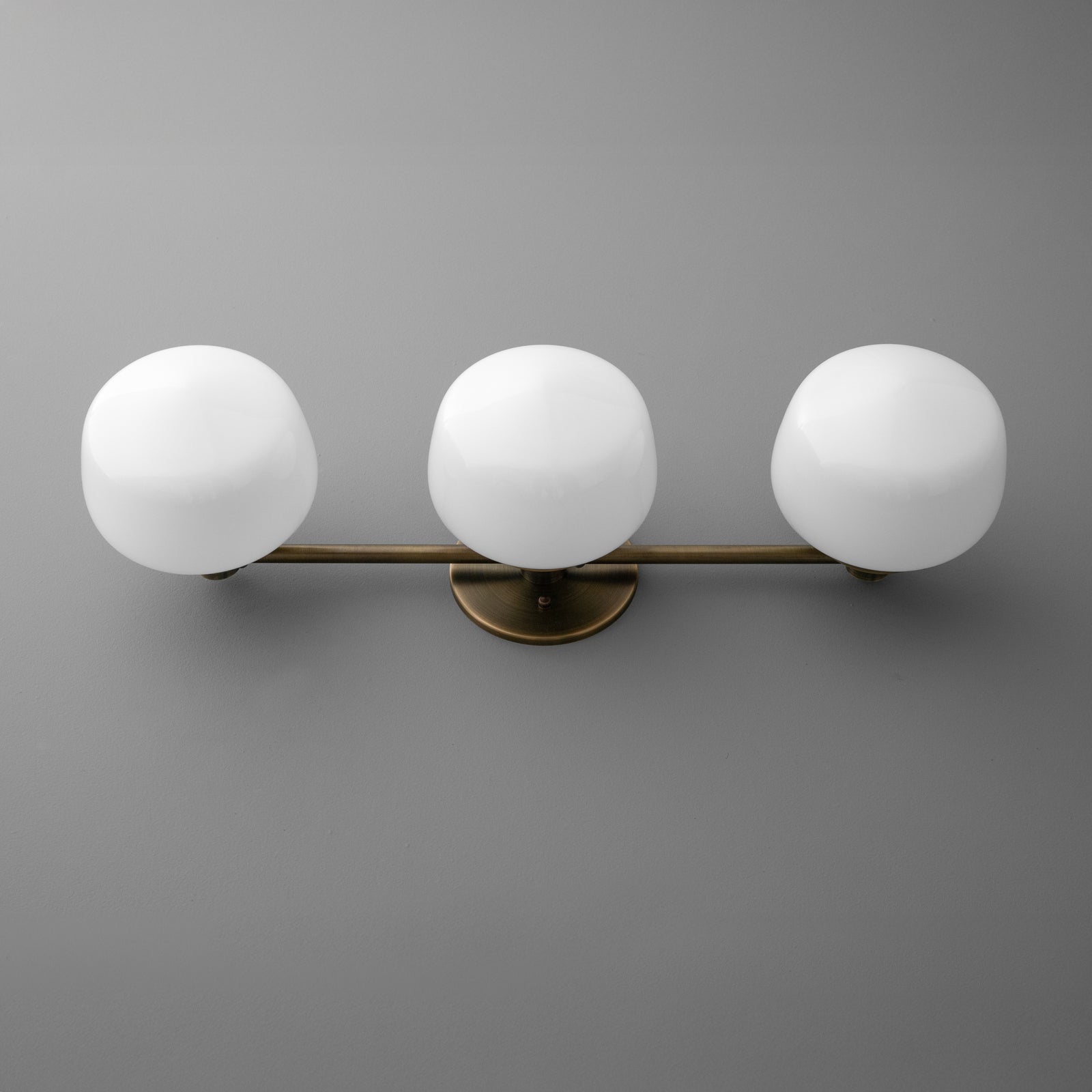Wall-mounted vanity light with three round white glass globes on a horizontal bronze base. - VANITY LIGHT MODEL NO. 1106