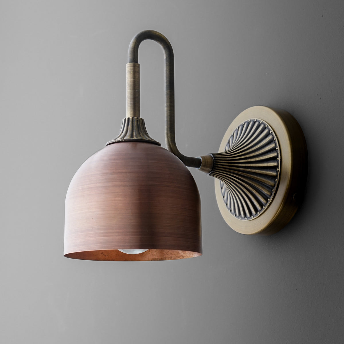 Wall-mounted sconce with matte copper dome shade and antique brass curved arm on a decorative round base. - SCONCE MODEL NO. 3046