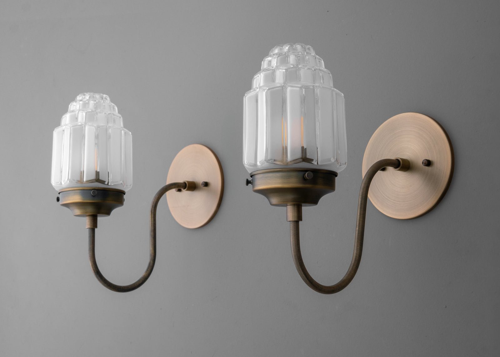 Vintage brass wall sconce with curved arm and ribbed glass shade featuring decorative top detail. - SCONCE MODEL NO. 1074