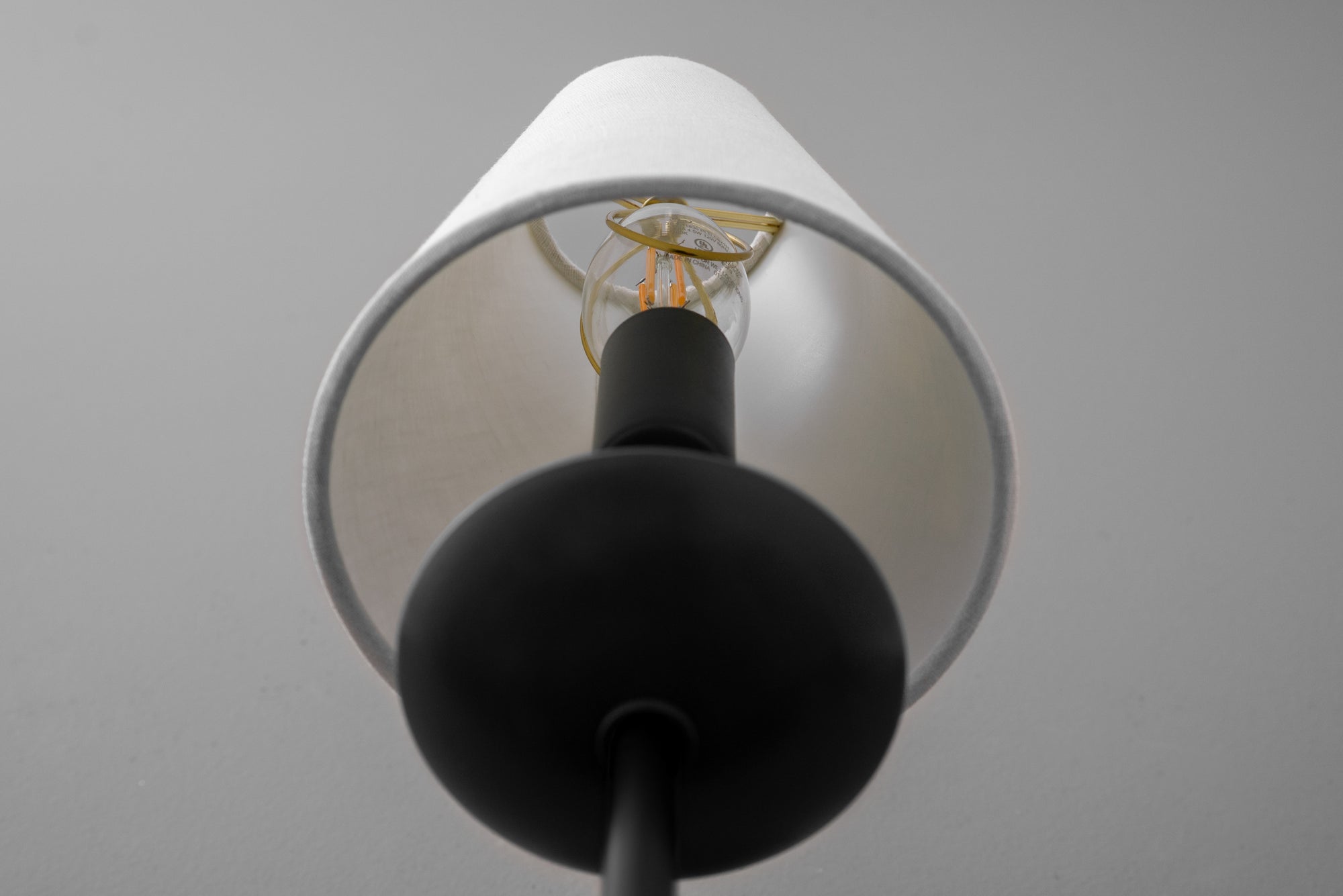Black metal wall sconce with white tapered fabric shade and visible filament bulb. - SCONCE MODEL NO. 9867