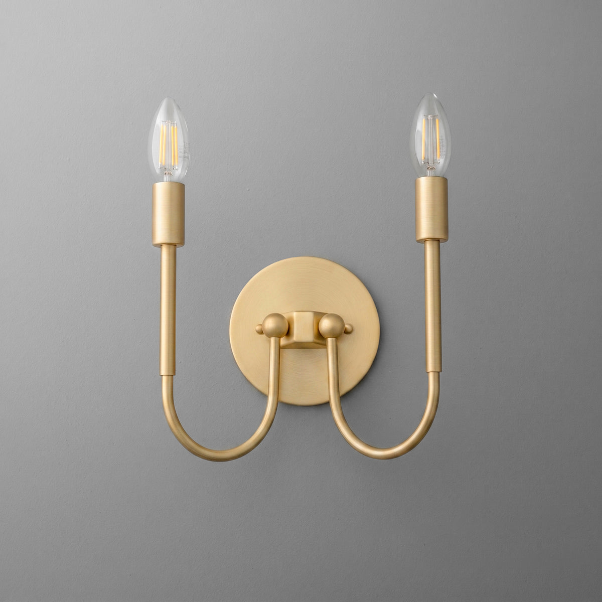Matte gold double-arm wall sconce with two candle-style bulbs and a round backplate. - SCONCE MODEL NO. 4122