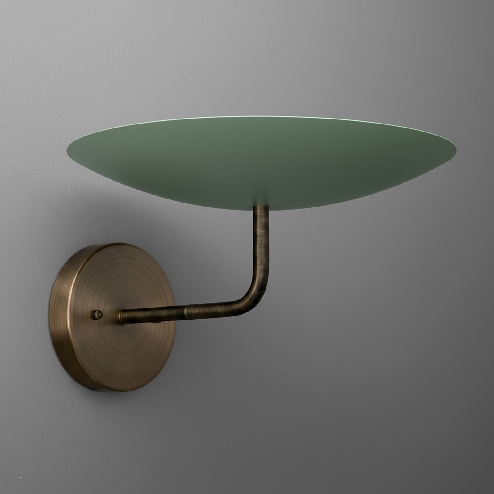 Wall sconce with aged brass round base and arm supporting a large flat green glass shade. - SCONCE MODEL NO. 1504