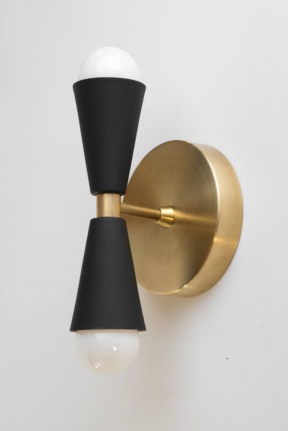Mid-century modern up/down sconce with matte black cones and raw brass round backplate. - SCONCE MODEL NO. 4717