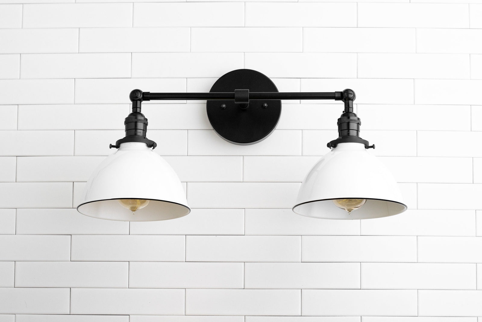 Industrial-style black metal vanity light with two white wide conical shades mounted on white tiled wall. - VANITY LIGHT MODEL NO. 4564