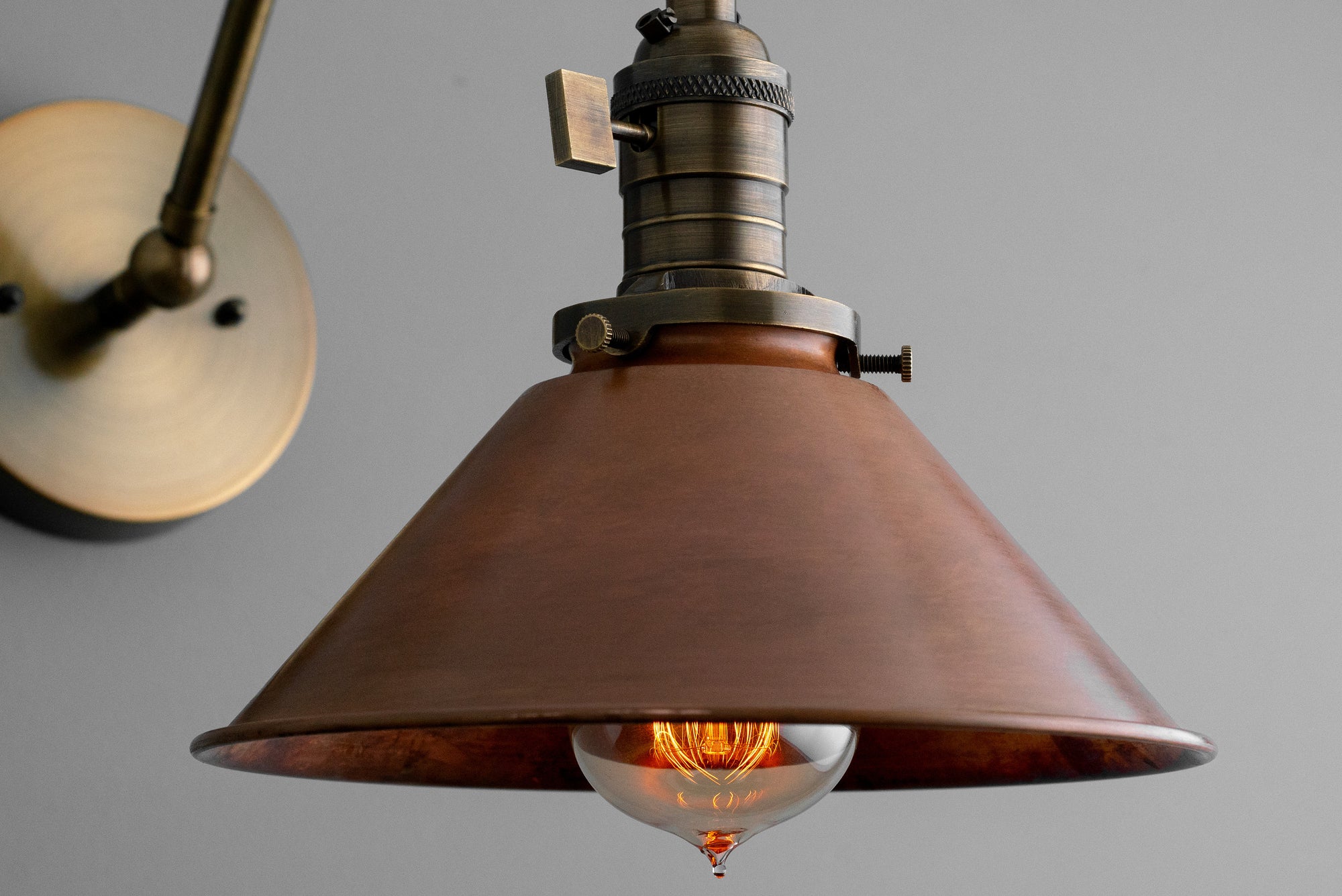 Adjustable industrial wall sconce with a wide conical antique brass shade and exposed filament bulb. - SCONCE MODEL NO. 6668
