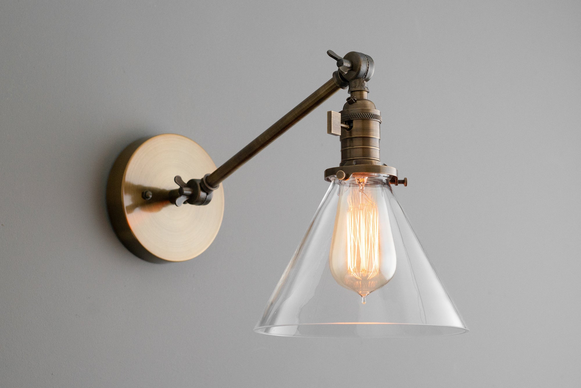 Adjustable antique brass industrial wall sconce with clear conical glass shade and exposed filament bulb. - SCONCE MODEL NO. 7962