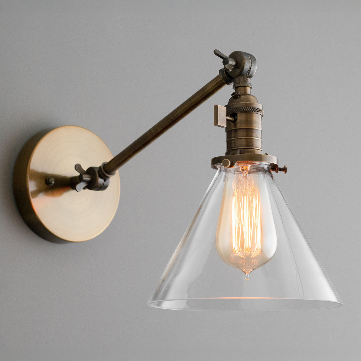 Adjustable antique brass industrial wall sconce with clear conical glass shade and Edison bulb. - SCONCE MODEL NO. 7962