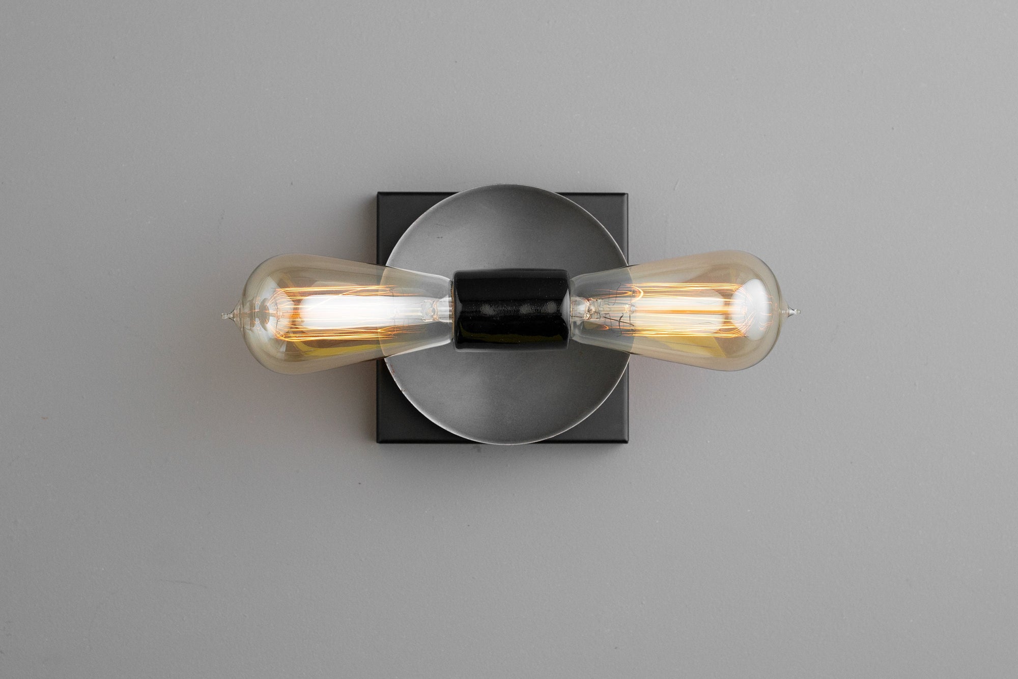 Industrial style black metal wall sconce with exposed filament bulbs and circular backplate. - SCONCE MODEL NO. 8169