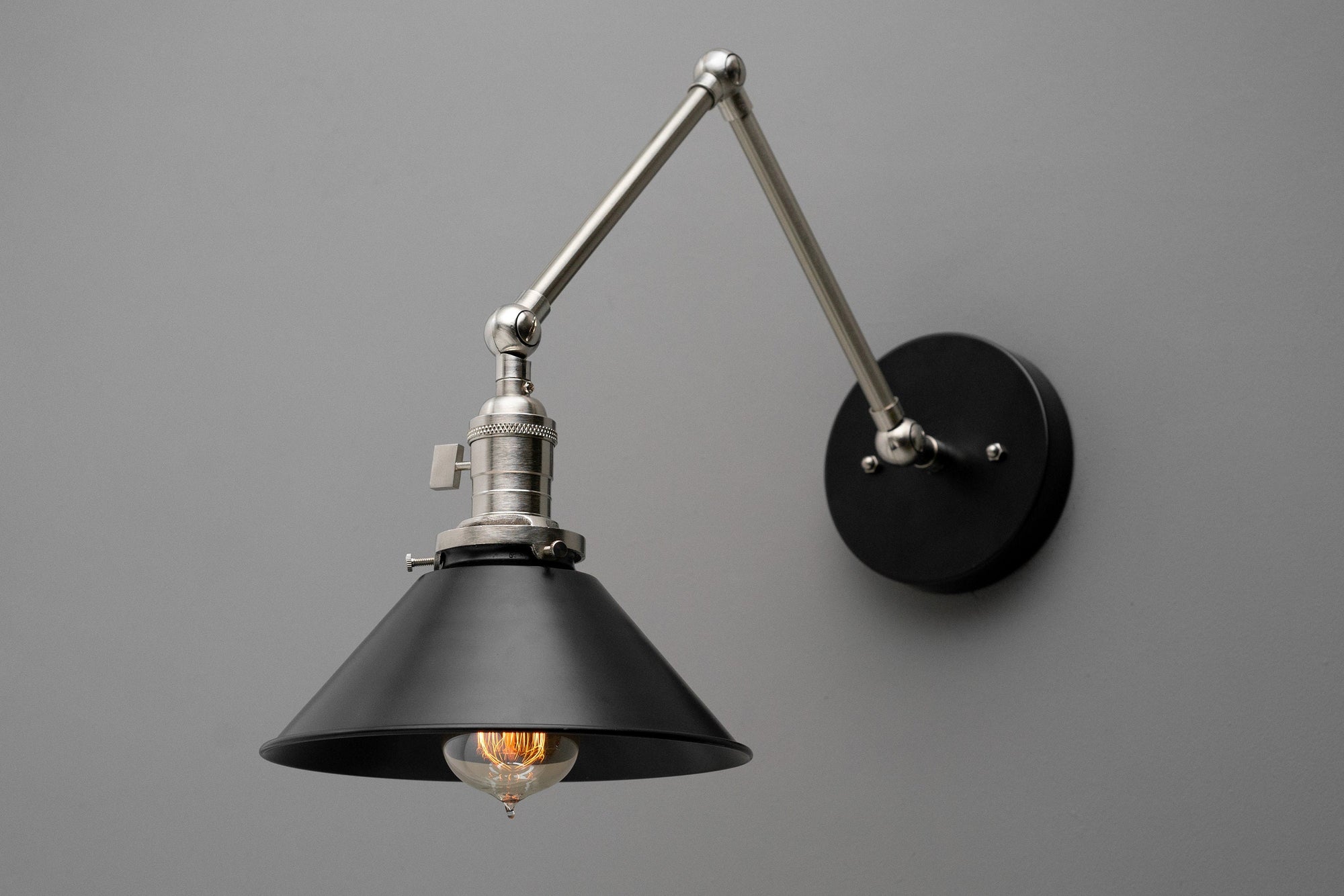 Adjustable industrial wall sconce with black metal shade and polished nickel arm on matte black mount. - SCONCE MODEL NO. 7164