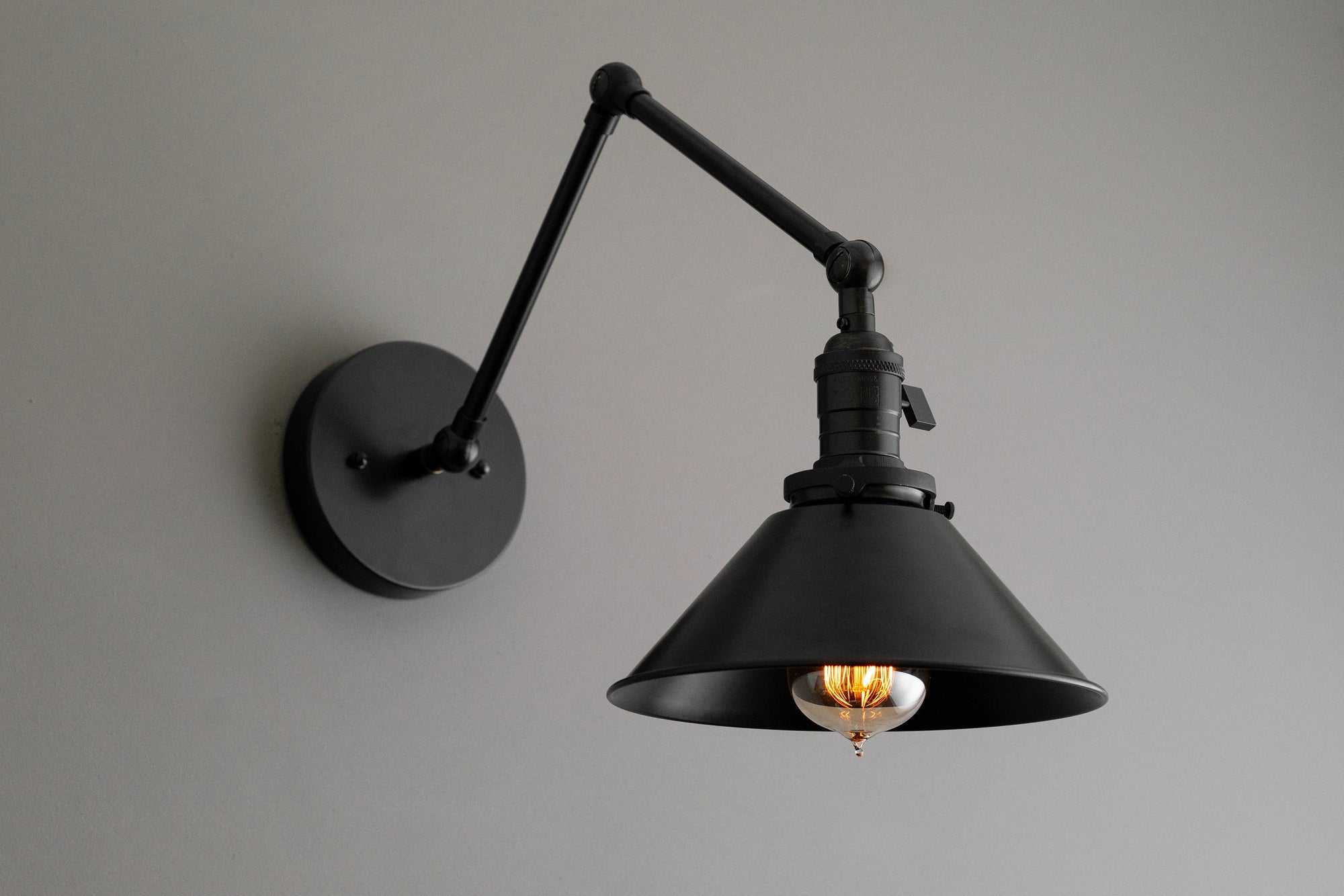 Adjustable black industrial wall sconce with metal shade and exposed filament bulb. - SCONCE MODEL NO. 7164