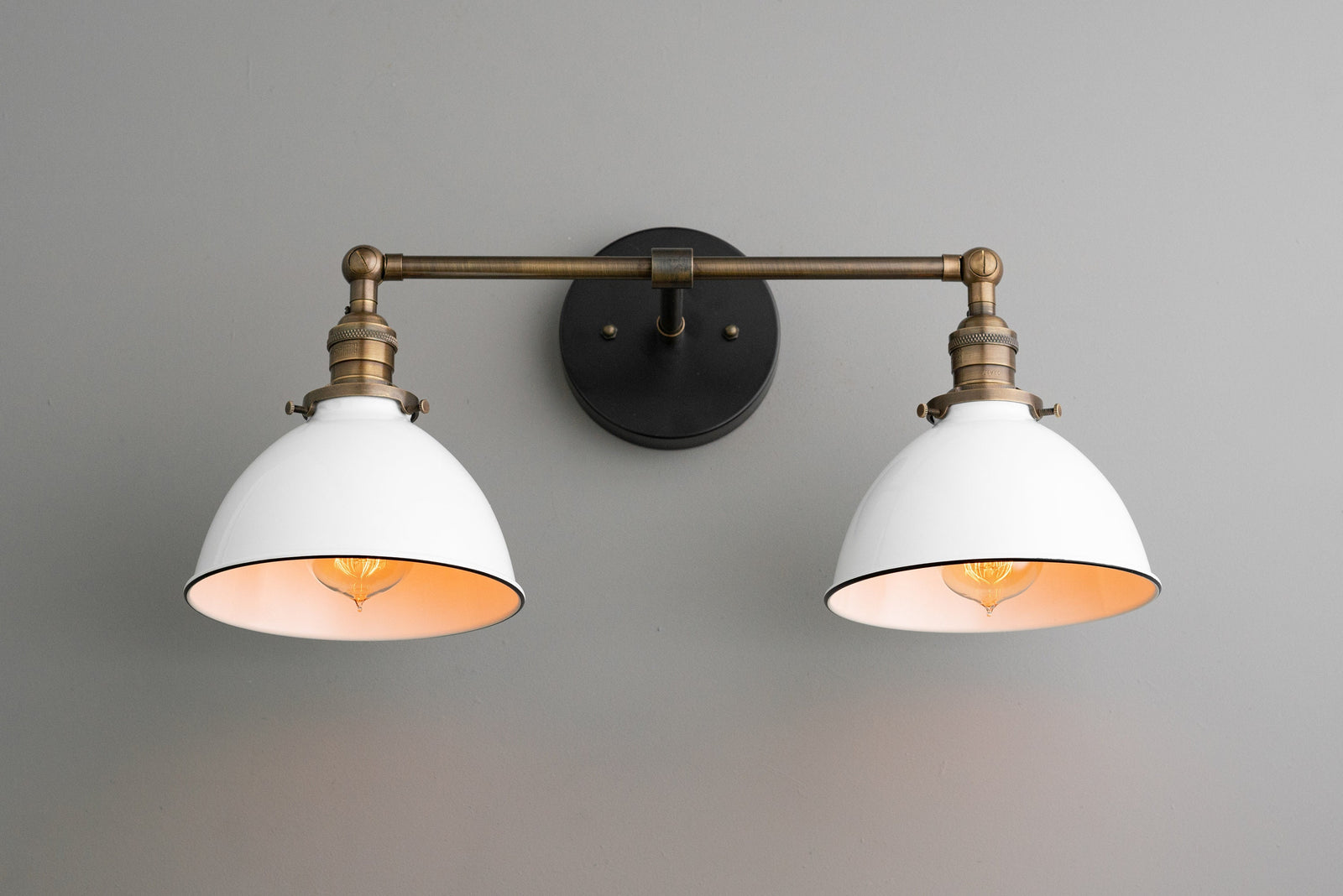 2-bulb vanity light with antique brass fixture and white industrial shades mounted on gray wall. - VANITY LIGHT MODEL NO. 4564