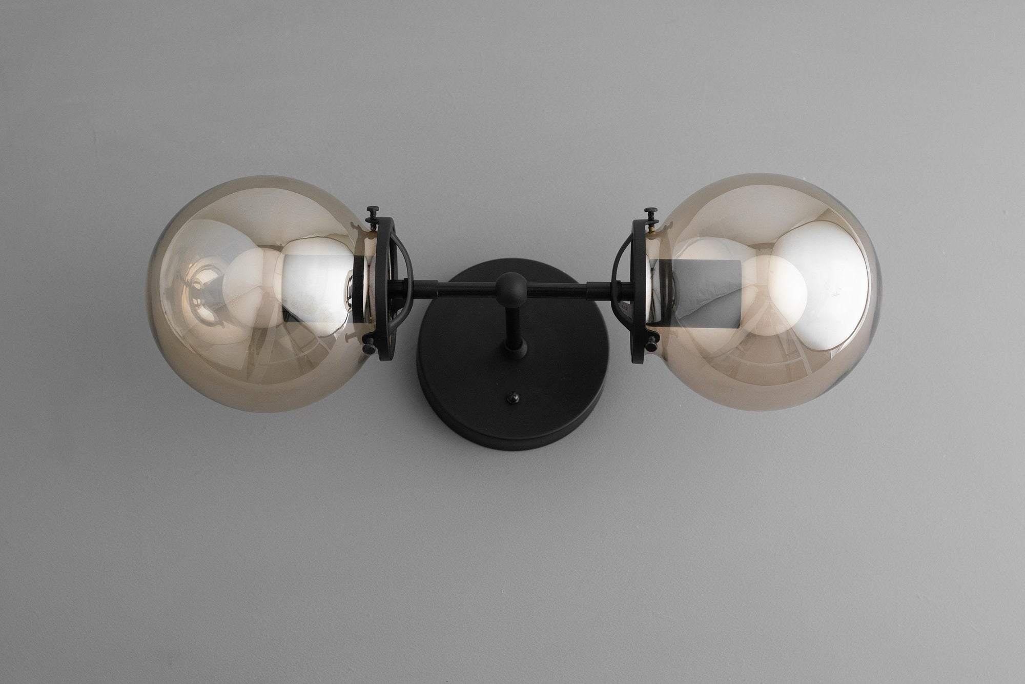 Mid-century modern black metal vanity light with two amber glass globe bulbs and round wall mount. - VANITY LIGHT MODEL NO. 8983