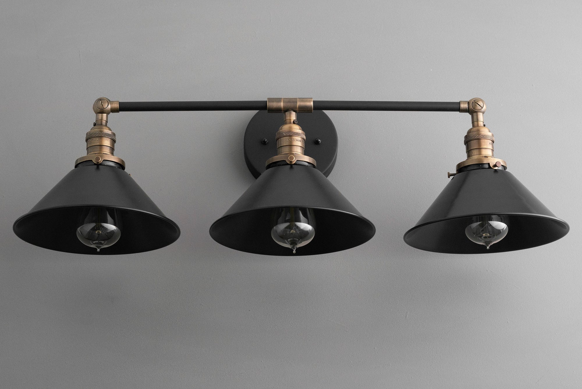 Industrial style black vanity light with three conical metal shades and antique brass accents. - VANITY LIGHT MODEL NO. 3406