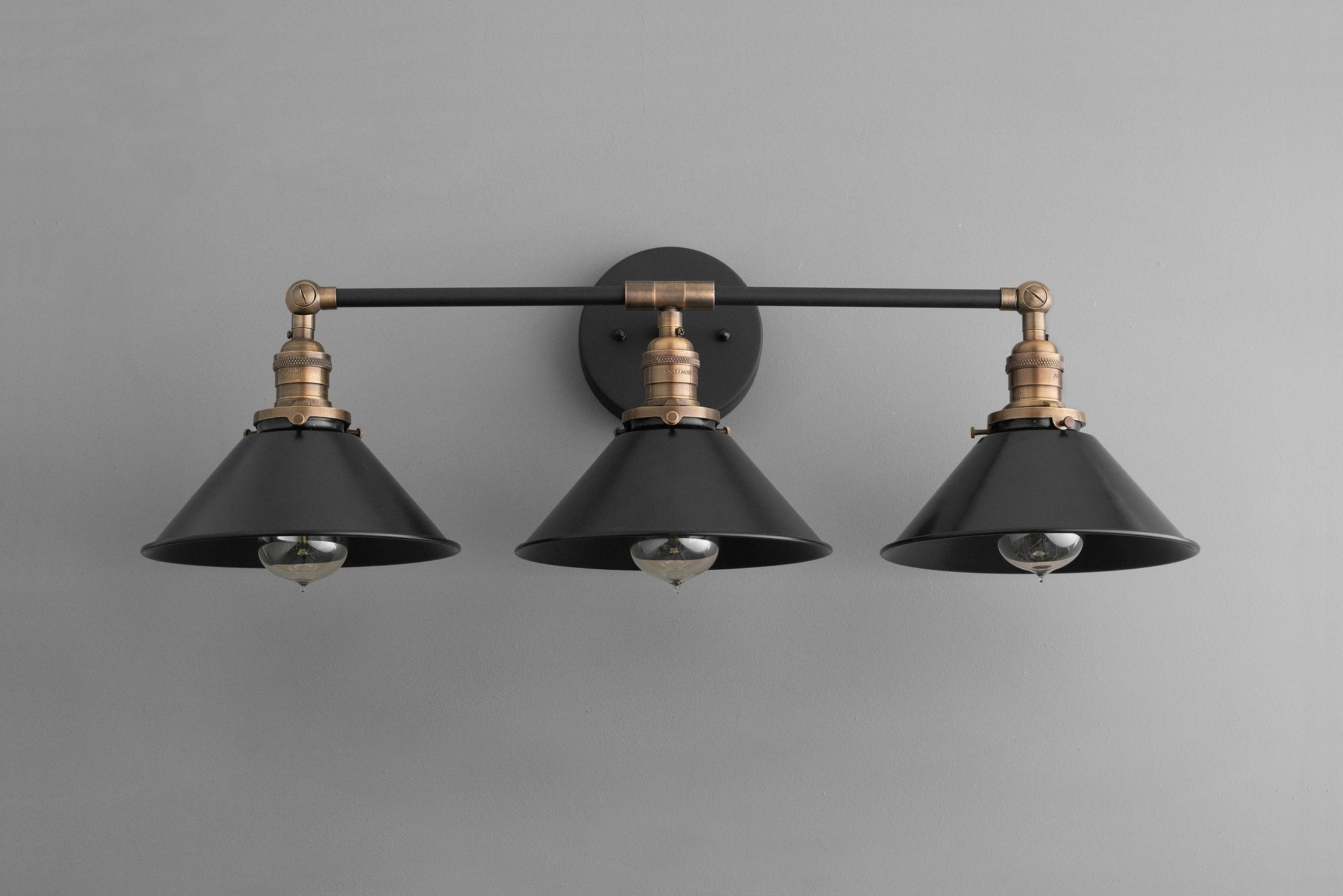 Three-bulb industrial vanity light with black metal shades and antique brass accents. - VANITY LIGHT MODEL NO. 3406