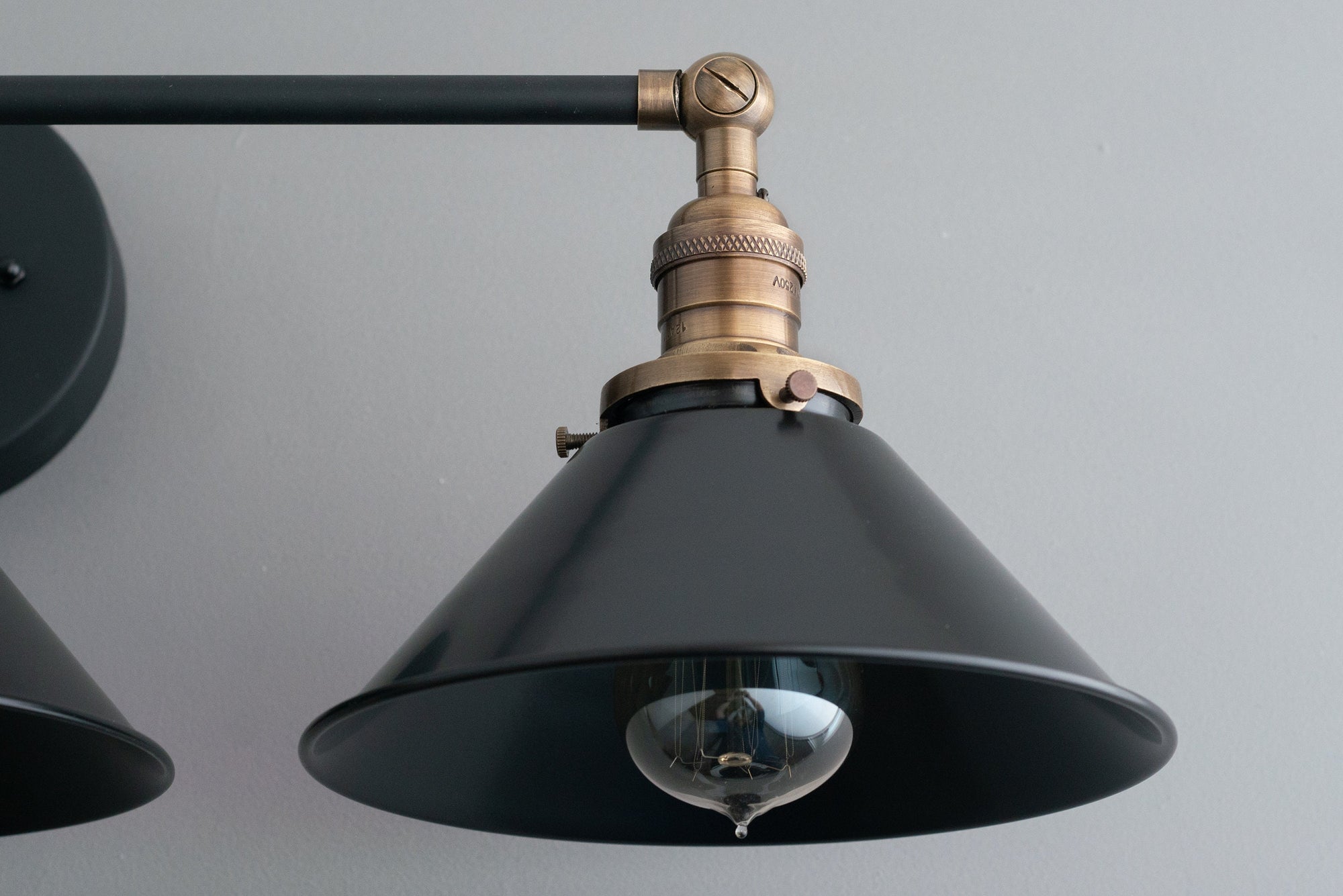 Industrial style black metal vanity light with antique brass accent and exposed bulb. - VANITY LIGHT MODEL NO. 3406