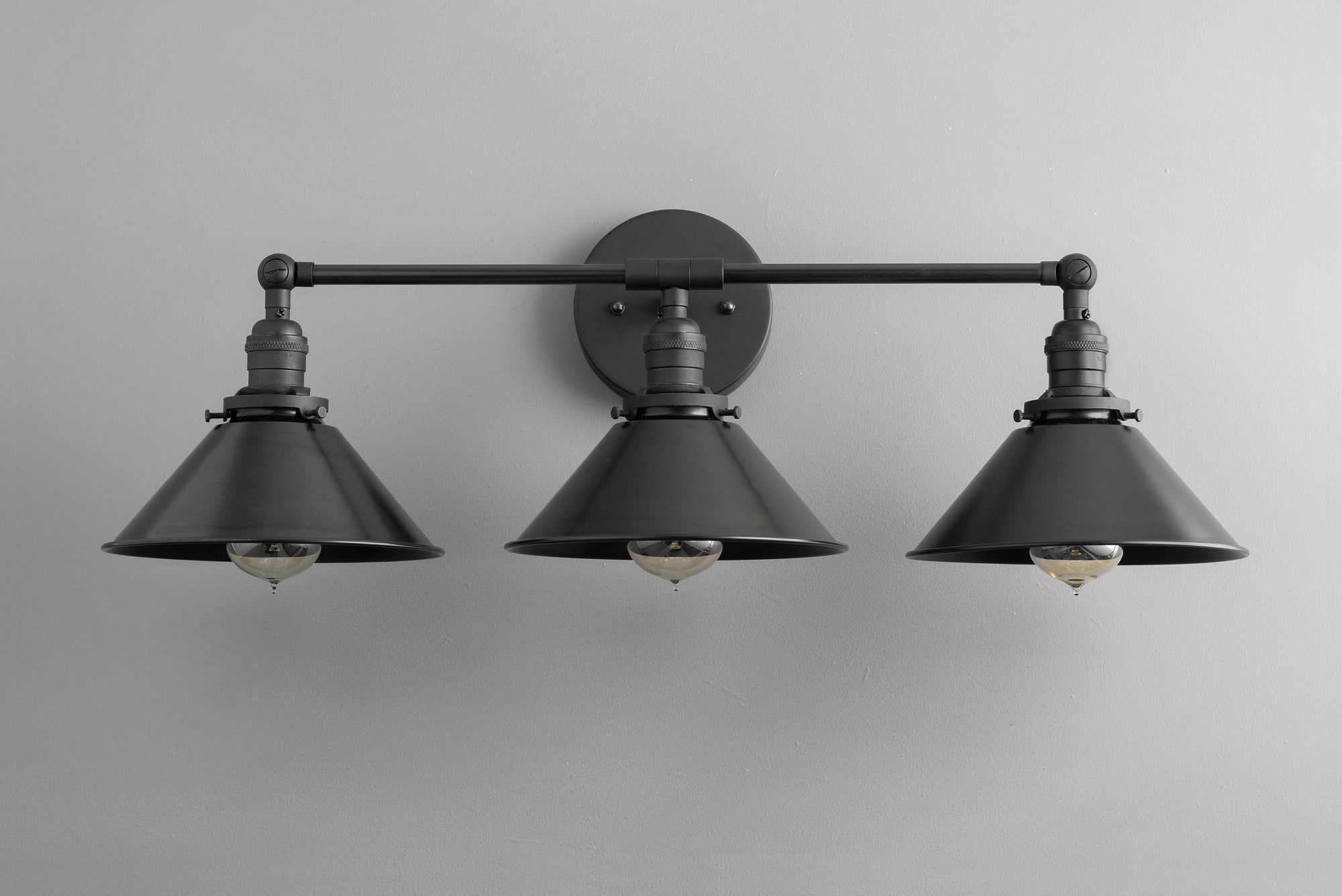 Industrial-style black metal vanity light with three conical shades and exposed bulbs. - VANITY LIGHT MODEL NO. 3406