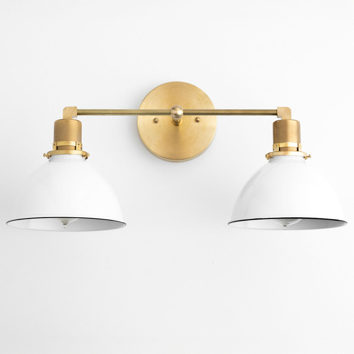 Two-light vanity light with White metal dome shades on a Raw or Sealed Brass bar and round wall plate. - VANITY LIGHT MODEL NO. 9018