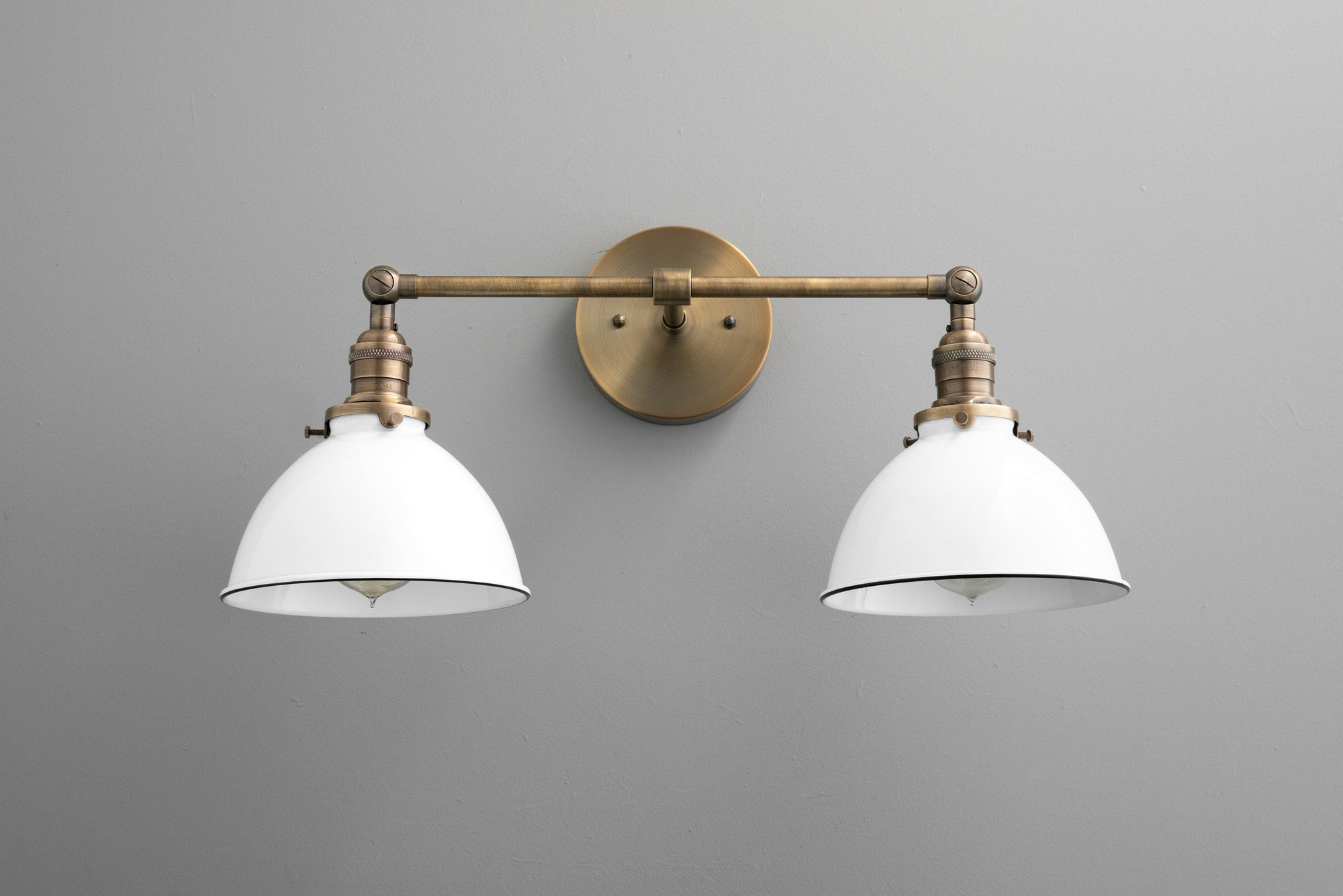 Two-bulb vanity light with antique brass finish and white industrial-style metal shades. - VANITY LIGHT MODEL NO. 4564