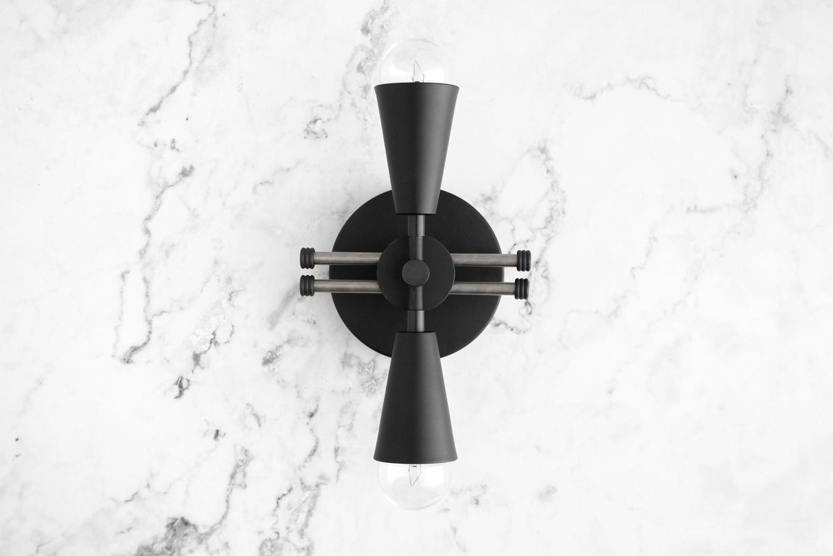 Black metal Art Deco sconce with two bare bulbs pointing up and down mounted on a white marble wall. - SCONCE MODEL NO. 3419