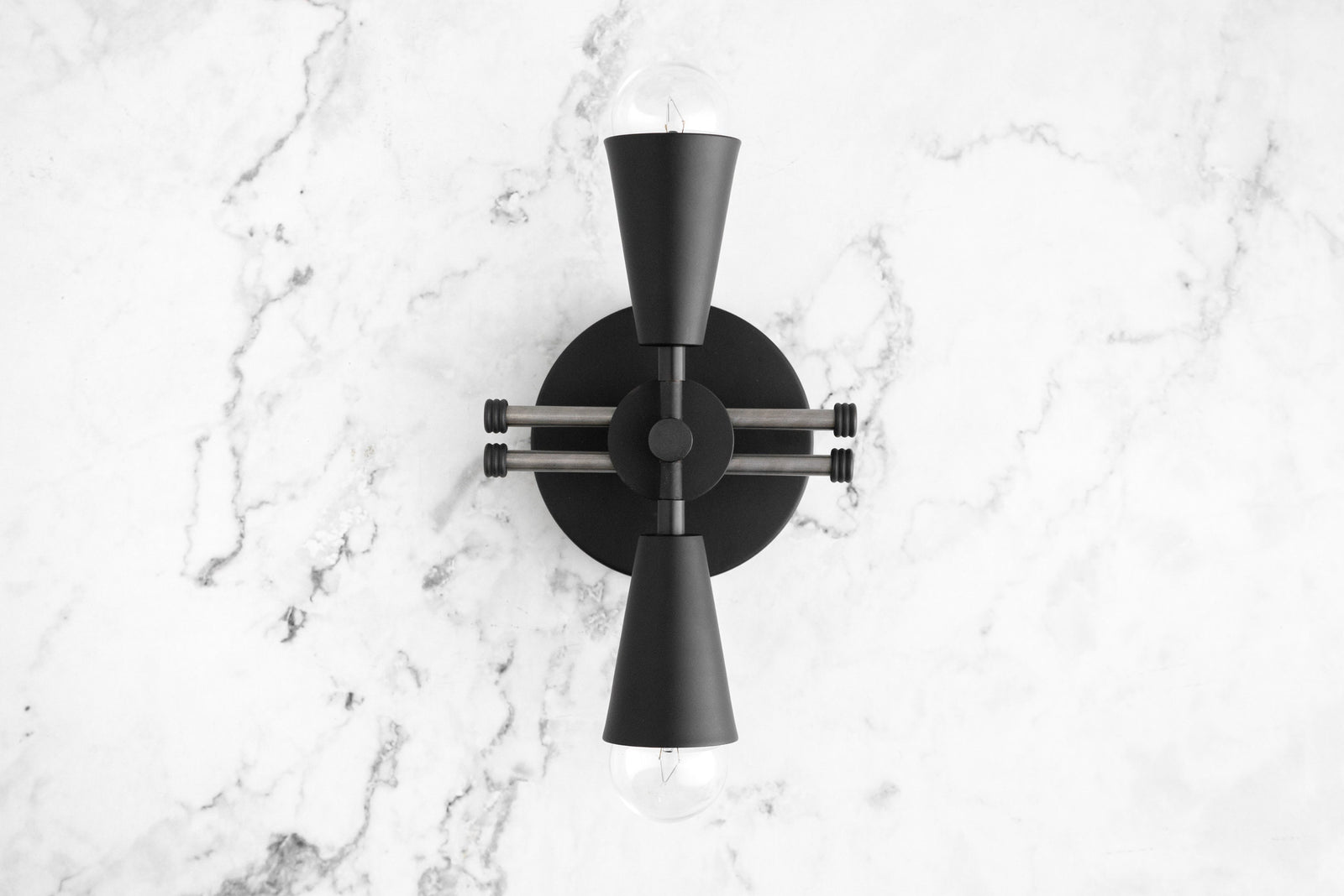 Black metal Art Deco sconce with two bare bulbs pointing up and down mounted on a white marble wall. - SCONCE MODEL NO. 3419
