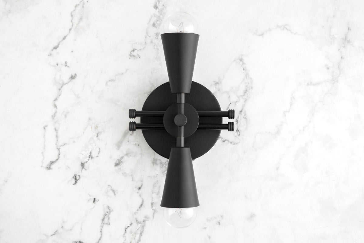 Black Art Deco sconce with double cone-shaped shades and exposed bulb on marble wall. - SCONCE MODEL NO. 3419