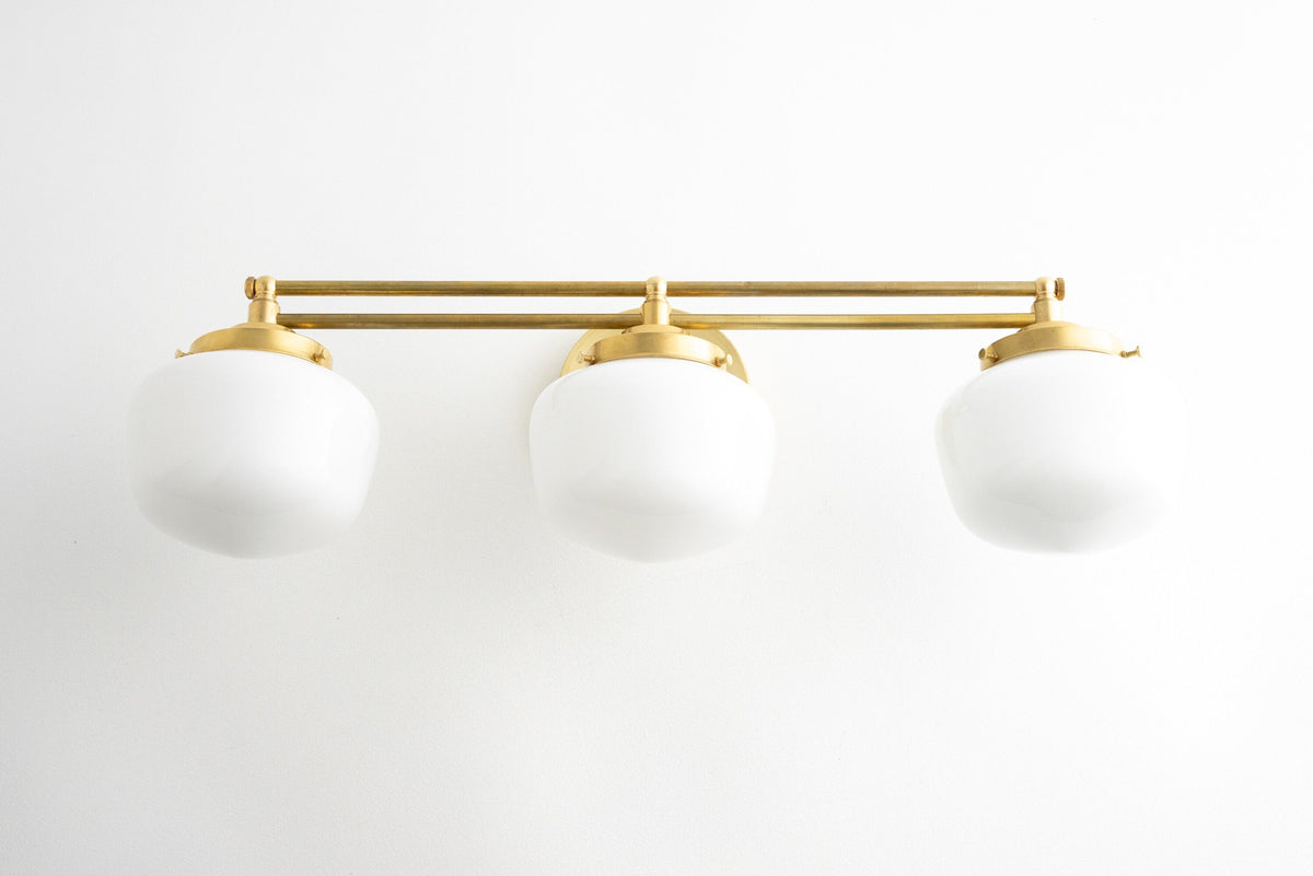 Three-bulb vanity light with polished brass finish and white globe shades in Art Deco style. - VANITY LIGHT MODEL NO. 4352