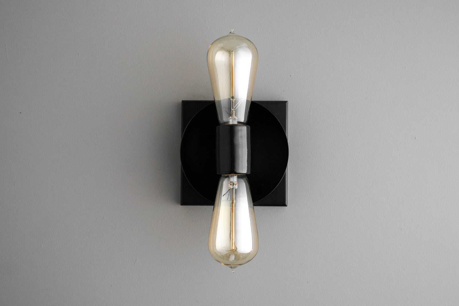 Industrial black metal wall sconce with exposed up and down Edison bulbs and square backplate. - SCONCE MODEL NO. 8169