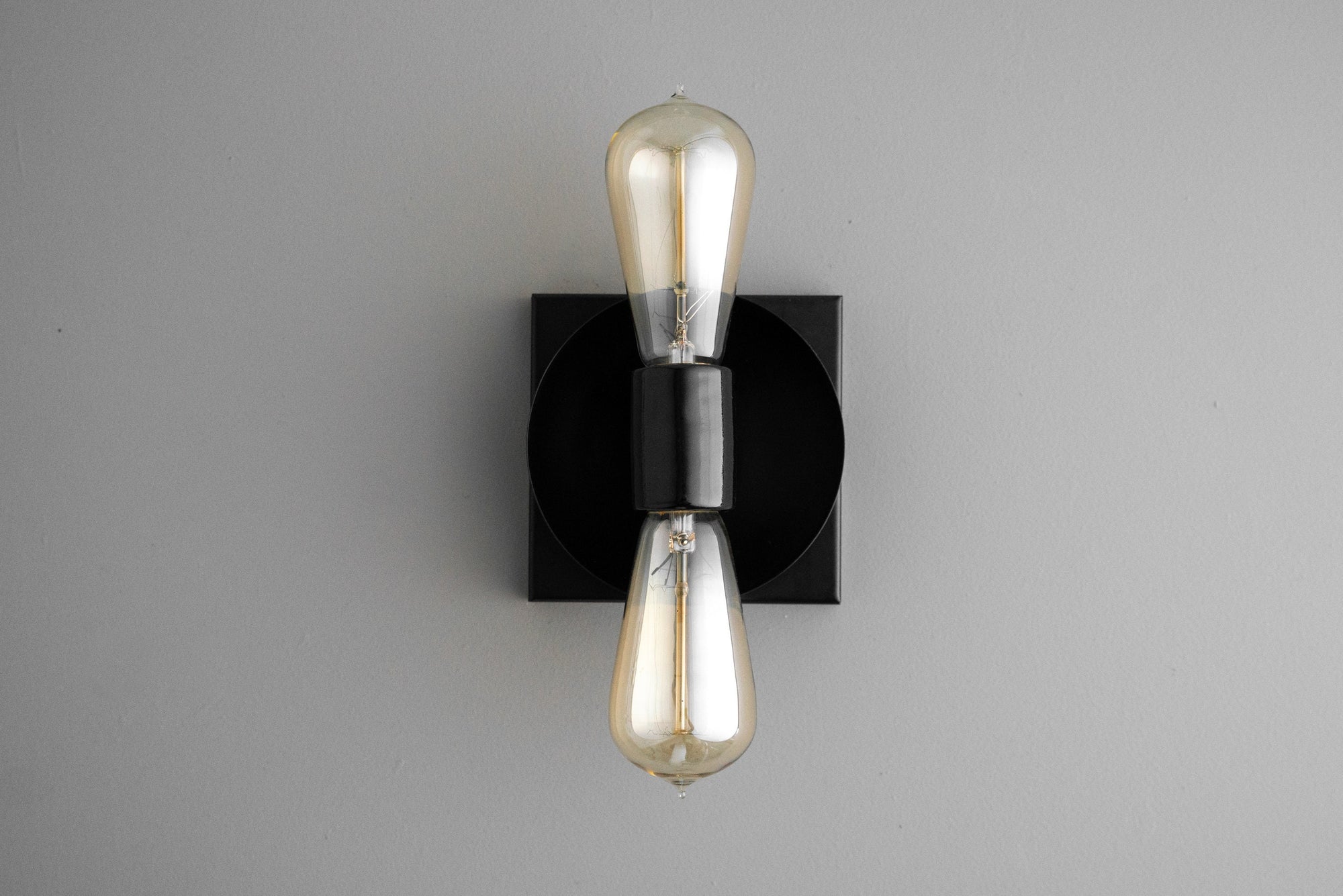 Industrial black metal wall sconce with exposed up and down Edison bulbs and square backplate. - SCONCE MODEL NO. 8169