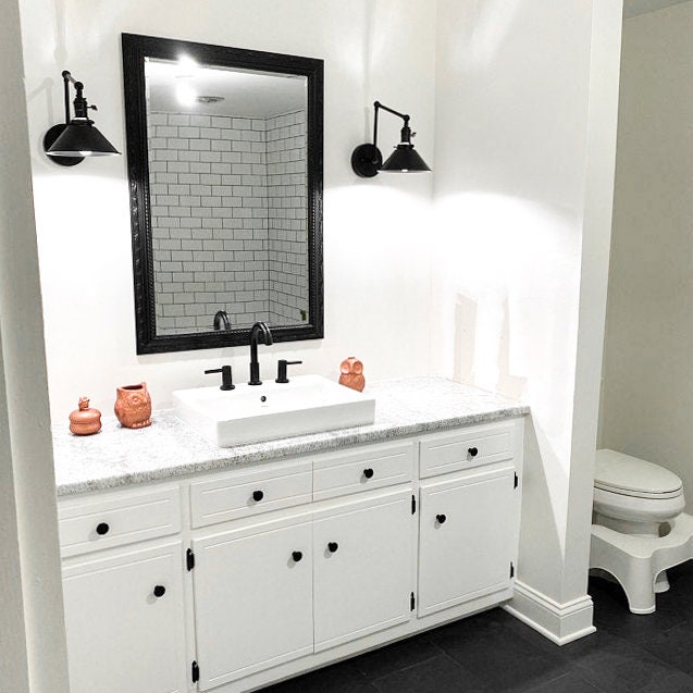 Black industrial adjustable wall sconce with metal shade above white bathroom vanity. - SCONCE MODEL NO. 7164