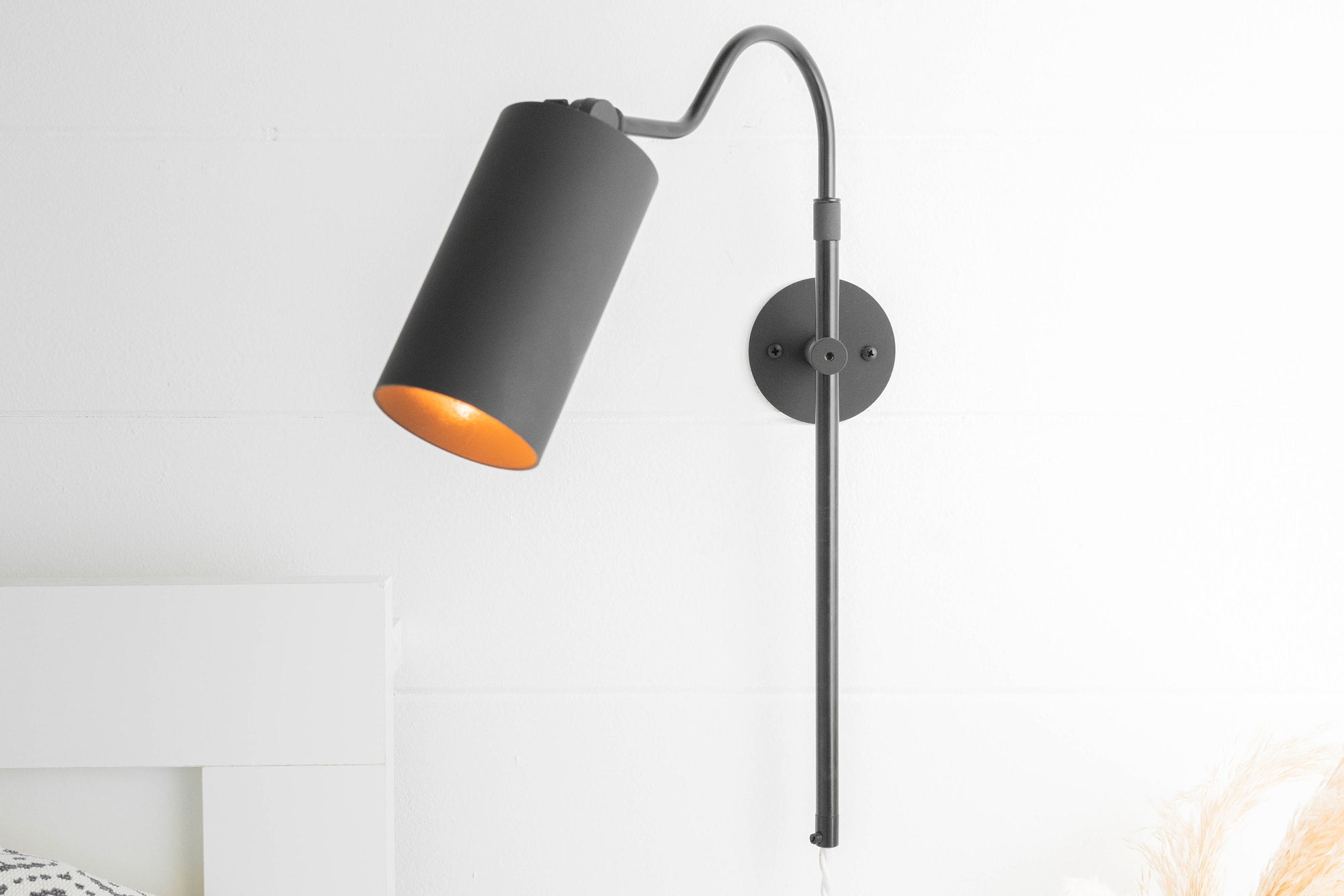 Matte black adjustable sconce with cylindrical shade and wall mount on white wall. - SCONCE MODEL NO. 1132