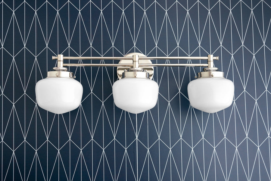 Three-bulb polished nickel vanity light with white globe shades mounted on dark geometric patterned wall. - VANITY LIGHT MODEL NO. 4352